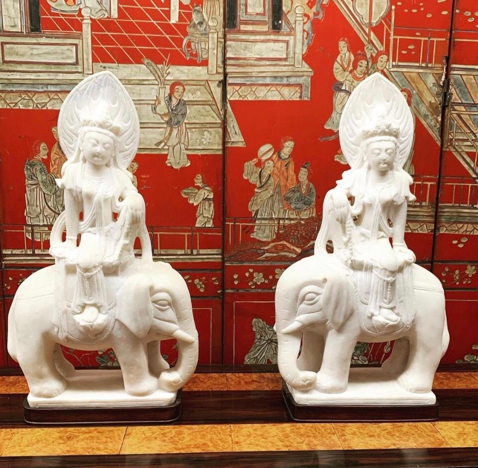 Pair Quan Yin marble figures riding elephants on wood bases.