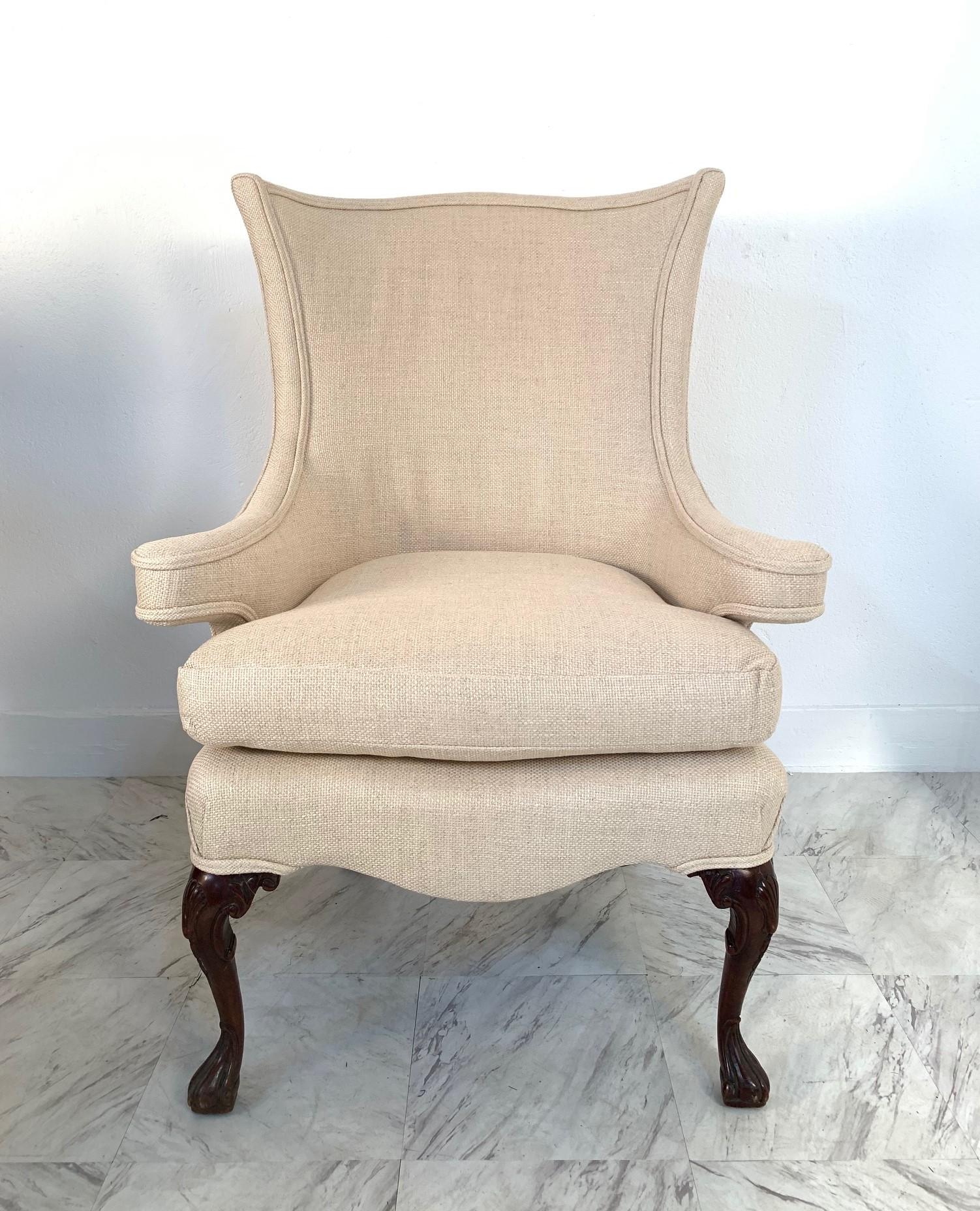 Pair of Queen Anne style wingback chairs upholstered in linen. Has mahogany claw feet.