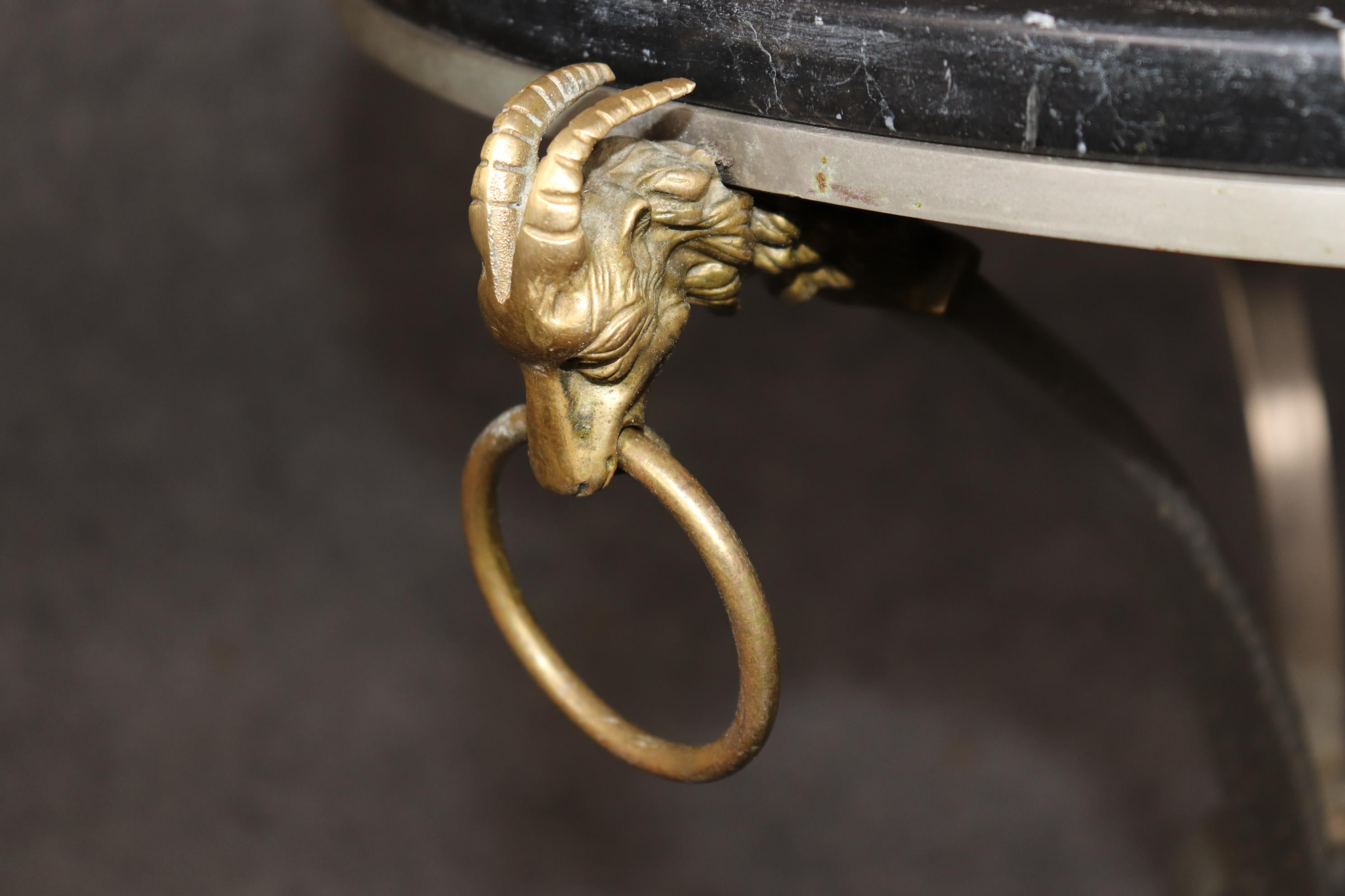 This is a stunning and rare pair of Maison bronze or brass Jansen rams head and steel gueridons or end tables. They date to the 1970s era and are in good original condition and feature wonderfully crafted ram's heads on steel bases with variegated