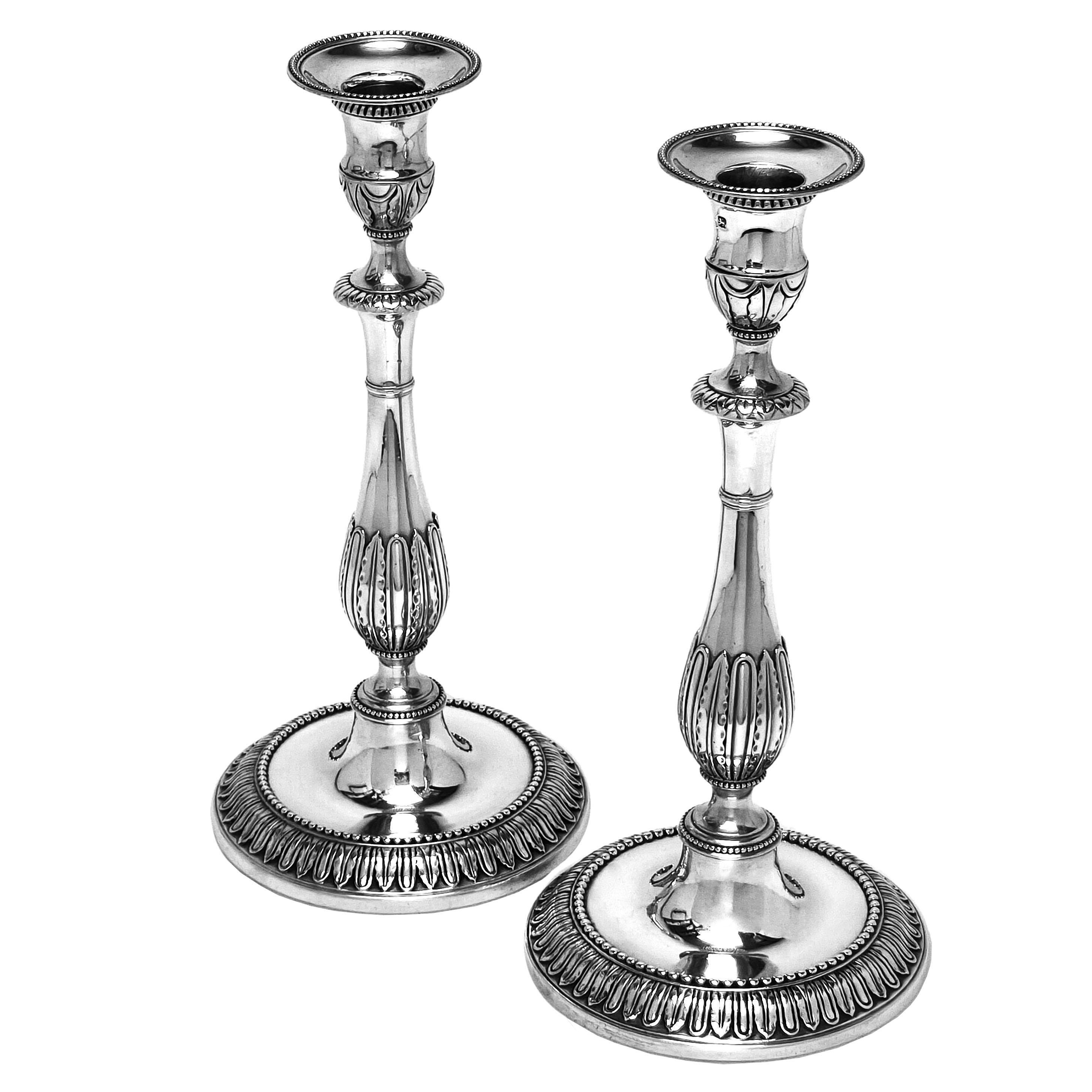 Una coppia di bellissimi candelieri antichi in argento sterling di Giorgio III. Questi imponenti candelabri georgiani in argento fuso hanno basi rotonde e colonne sagomate impreziosite da bande di motivi. I candelabri sono dotati di applique
