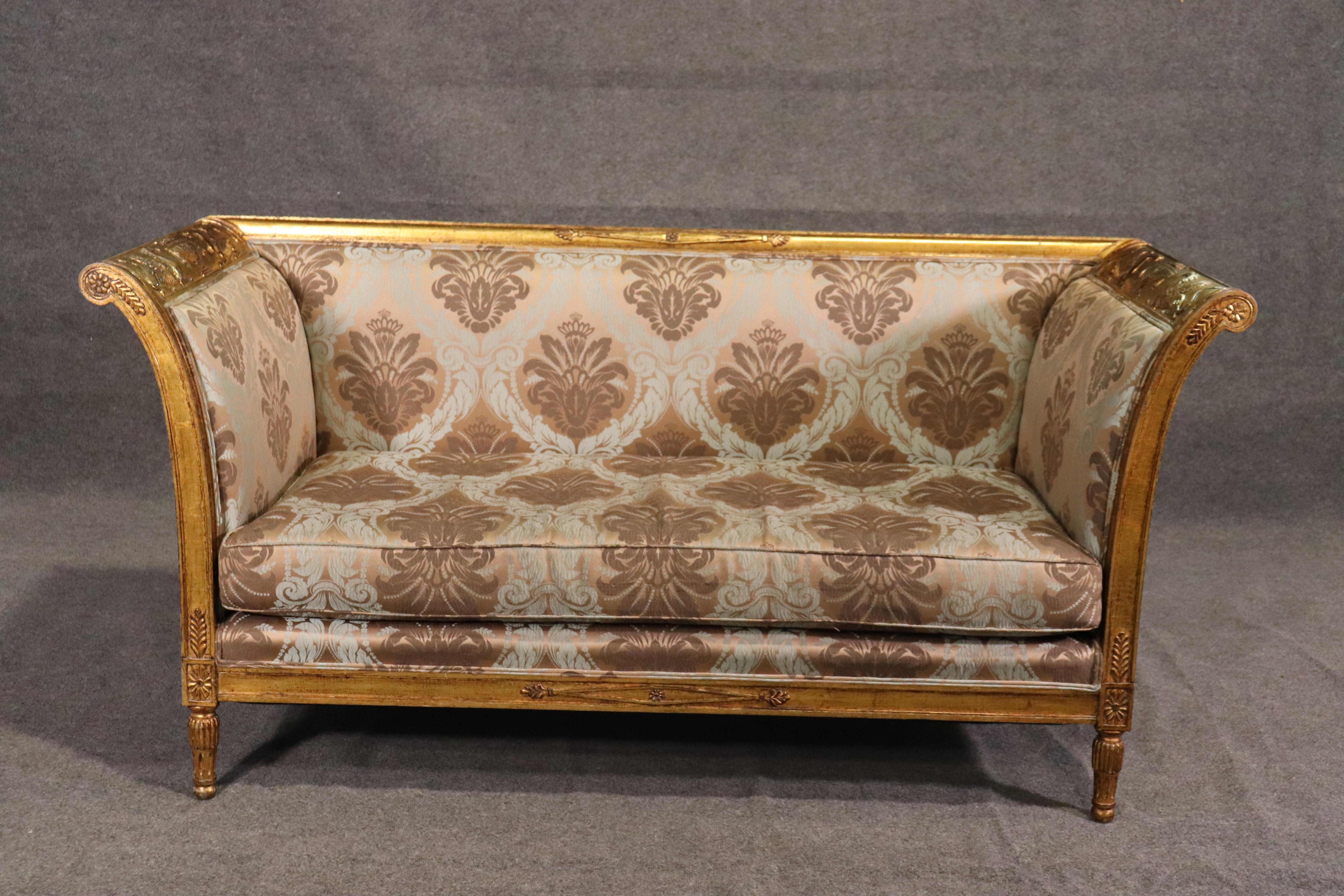 This is a fantastic pair of French Directoire style, Italian-made settees or sofas. They are each carved with griffins and traditional French element and graceful taste. The frames are beautifully carved and layered on genuine distressed gold leaf