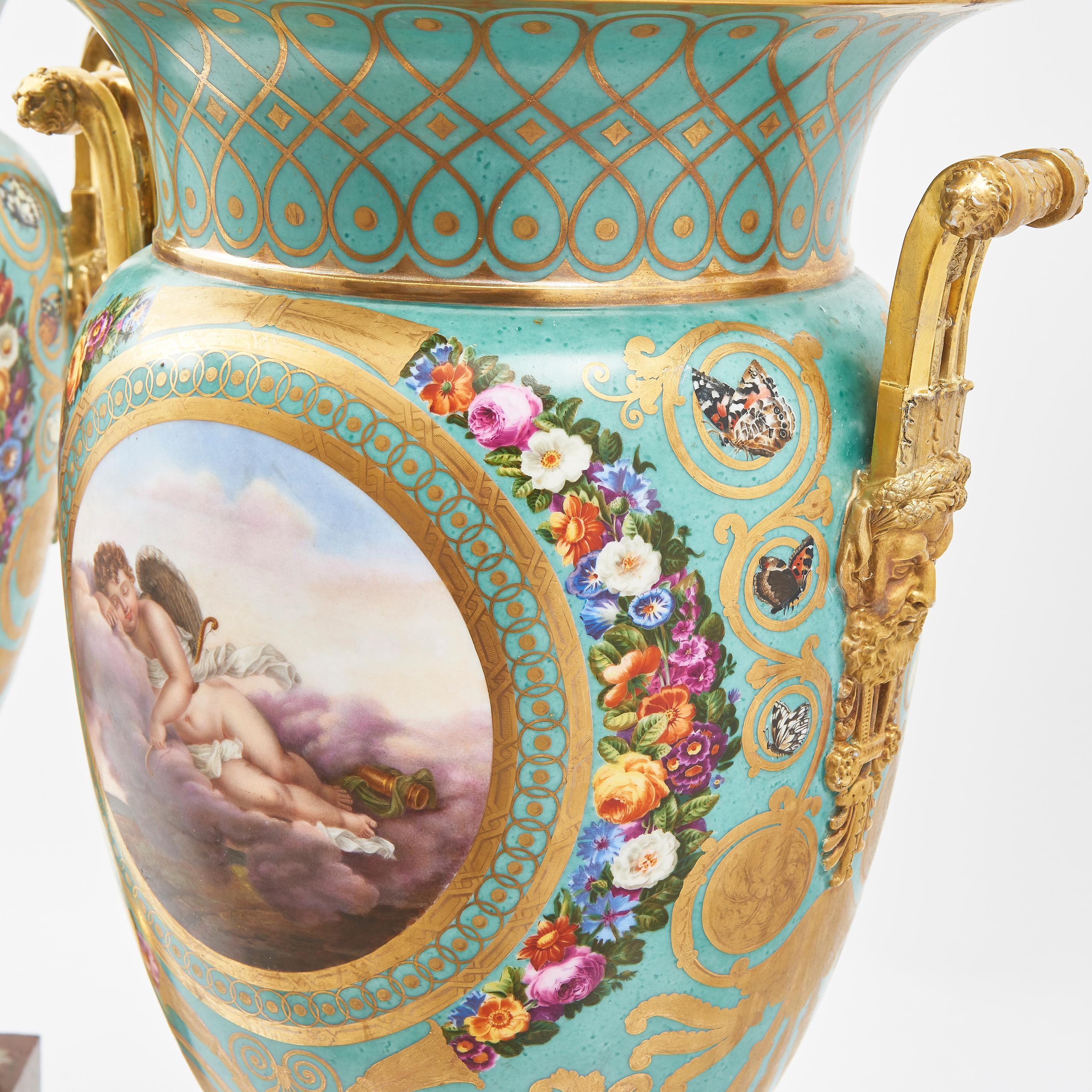Pair large Sevres urns with gilded handles and on marble bases. With finely painted scenes of cupids surrounded by garlands and the body in duck egg blue with gilt decoration.The base with underglazed blue crossed L’s for 1760, and the unglazed