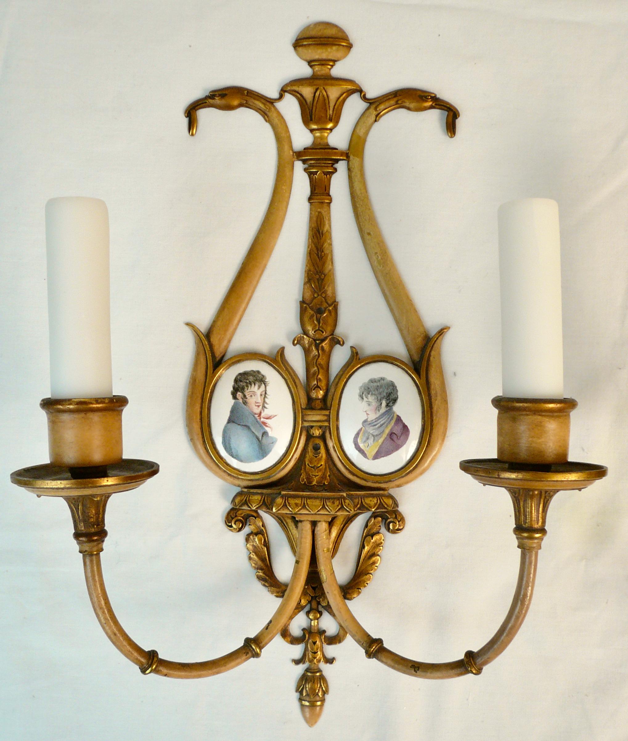 This pair of English Regency style partial gilt and polychrome painted sconces feature oval Battersea type enamel on copper 
