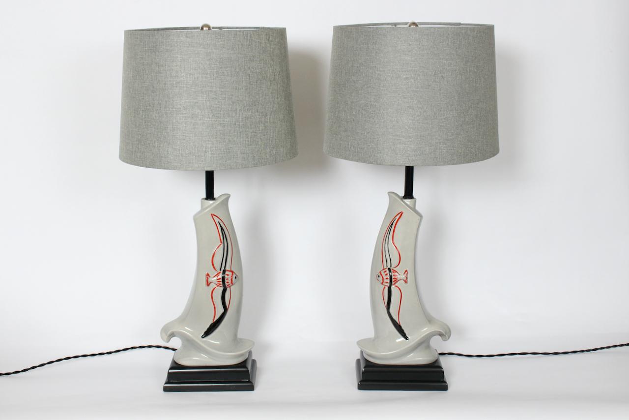 Pair Modern Rembrandt Lamp Company gray & red glazed ceramic fish lamps. 
Featuring asymmetric sculpted flared, reflective Dove Gray wave like cast gloss ceramic forms, raised flying fish in Red and Black line, Black enameled tubular stems,