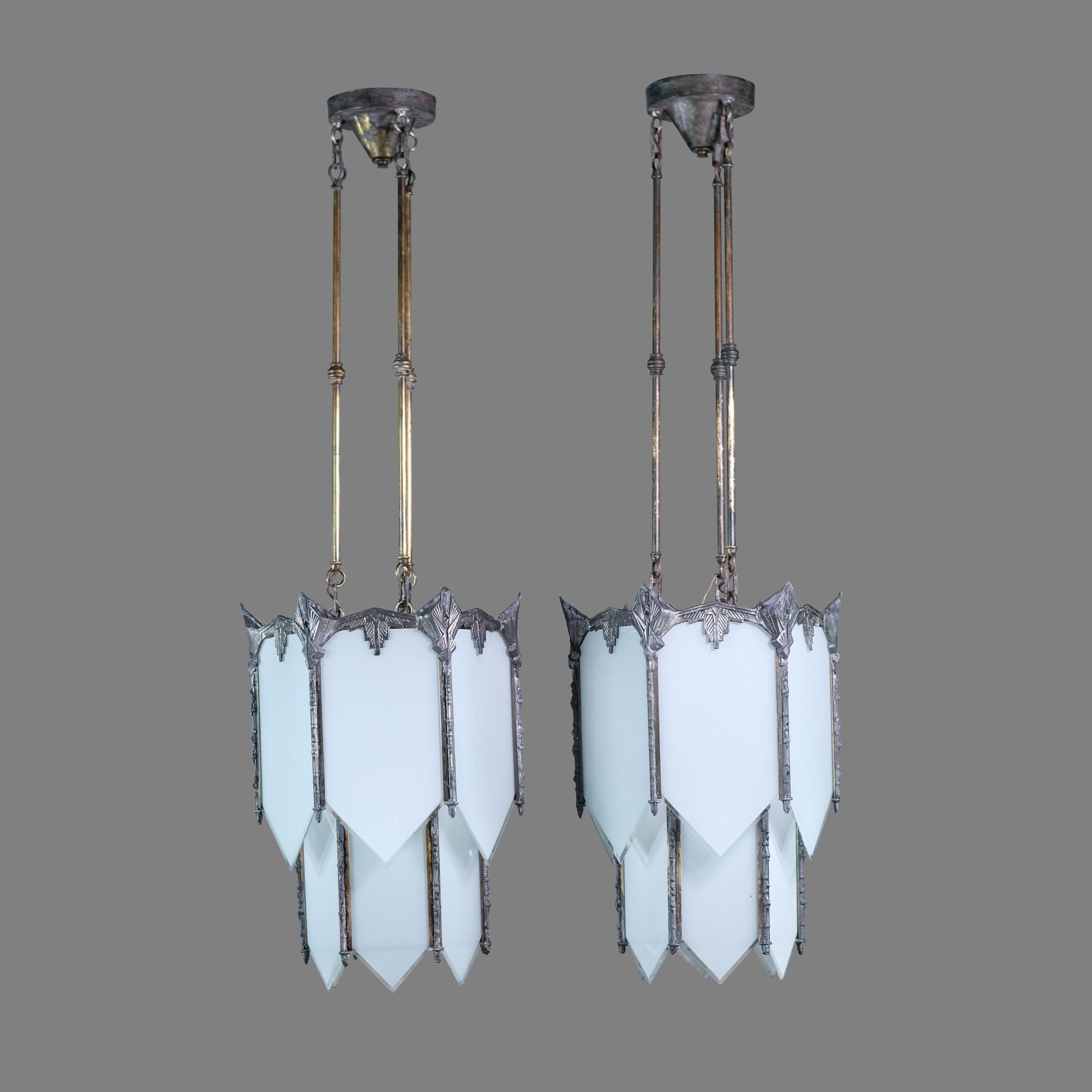 Early 20th century pendant lights done in an Art Deco style. Each fixture is nickel plated. White beveled glass completes this iconic look. Each light has three standard household E-26 lightbulb sockets. Cleaned and rewired. Chain allows the