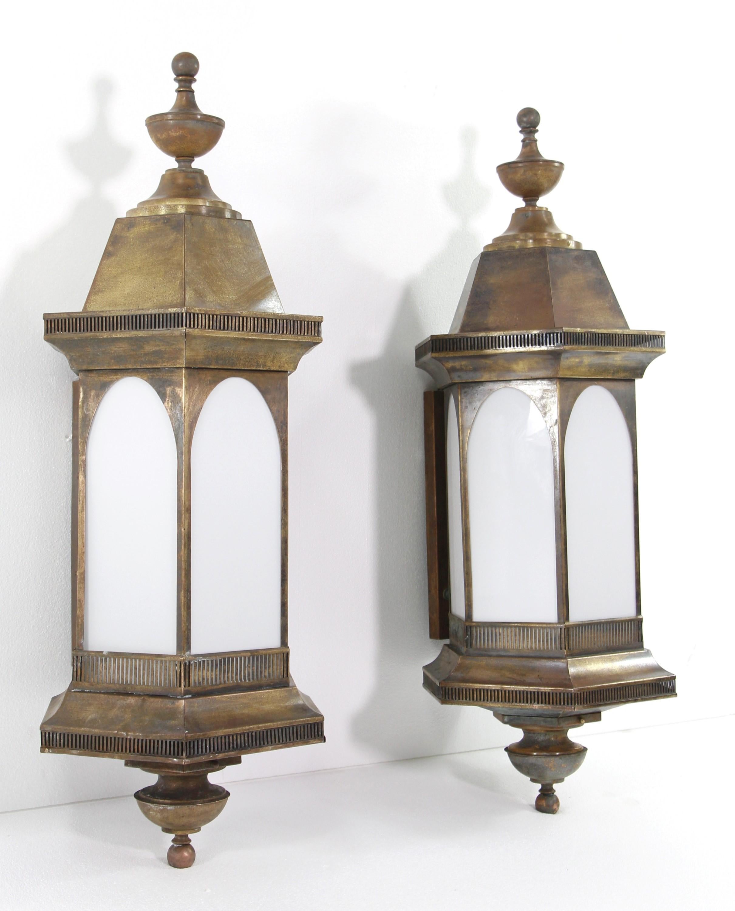 Early 20th century pair of exterior red brass wall sconces in an arched Gothic design. These feature white glass panes. Cleaned and restored. Priced as a pair.