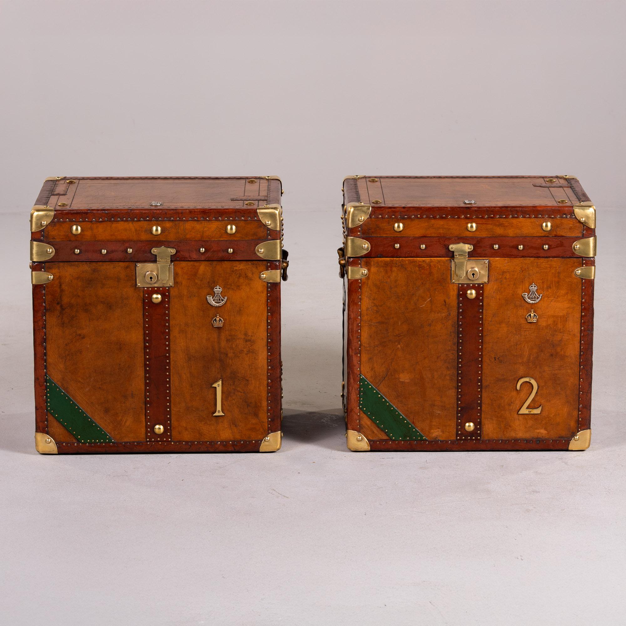Encontrados en Inglaterra, este par de baúles de cuero y latón de hacia 1920 han sido restaurados profesionalmente. El cuero ha sido reacondicionado y remendado donde era necesario. Los interiores se han revestido de terciopelo rojo y se han pulido