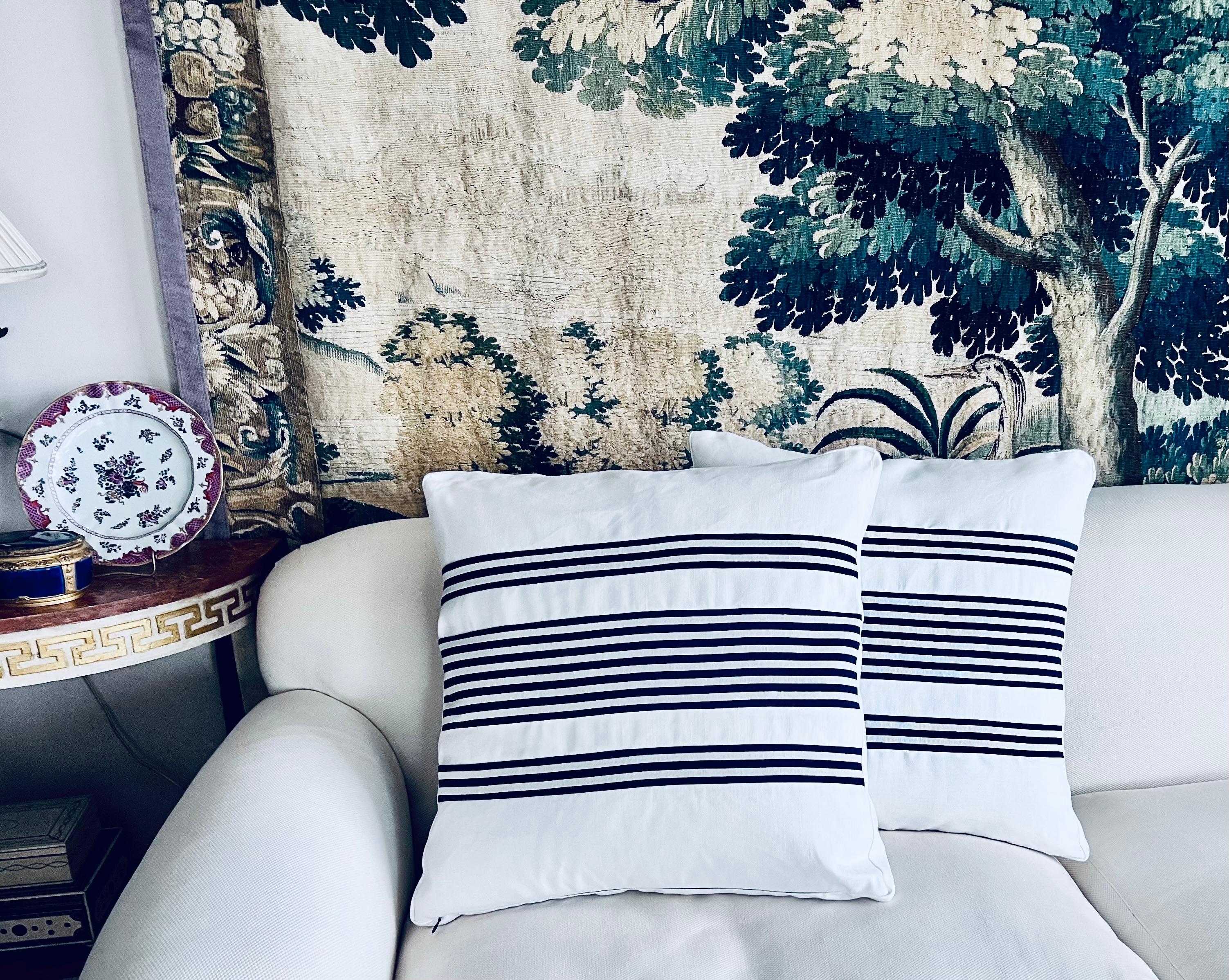 Pair of reversible cushions/pillows in a navy blue stripe on white.  These 22” square cushions/pillows have been made by a delicate hand.  The navy blue stripes have been carefully cut and set into the white fabric.  The white fabric has a linen