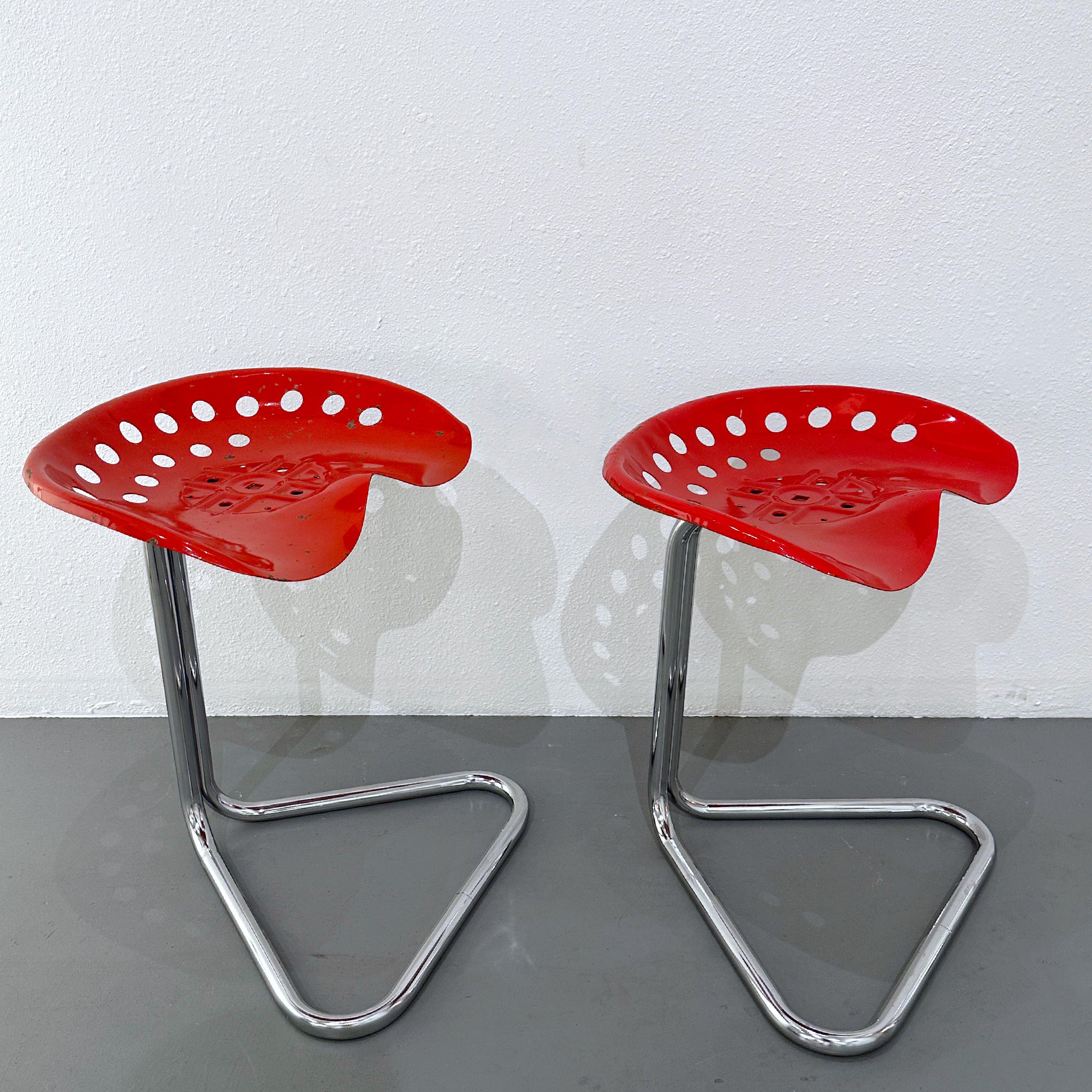 A pair of fabulous T7 Tractor seat stools designed by Rodney Kinsman, a British designer, for his company OMK in 1971. Truly an avant-garde design in a highly desirable red color. These stools feature a seat made from an actual tractor seat mold,
