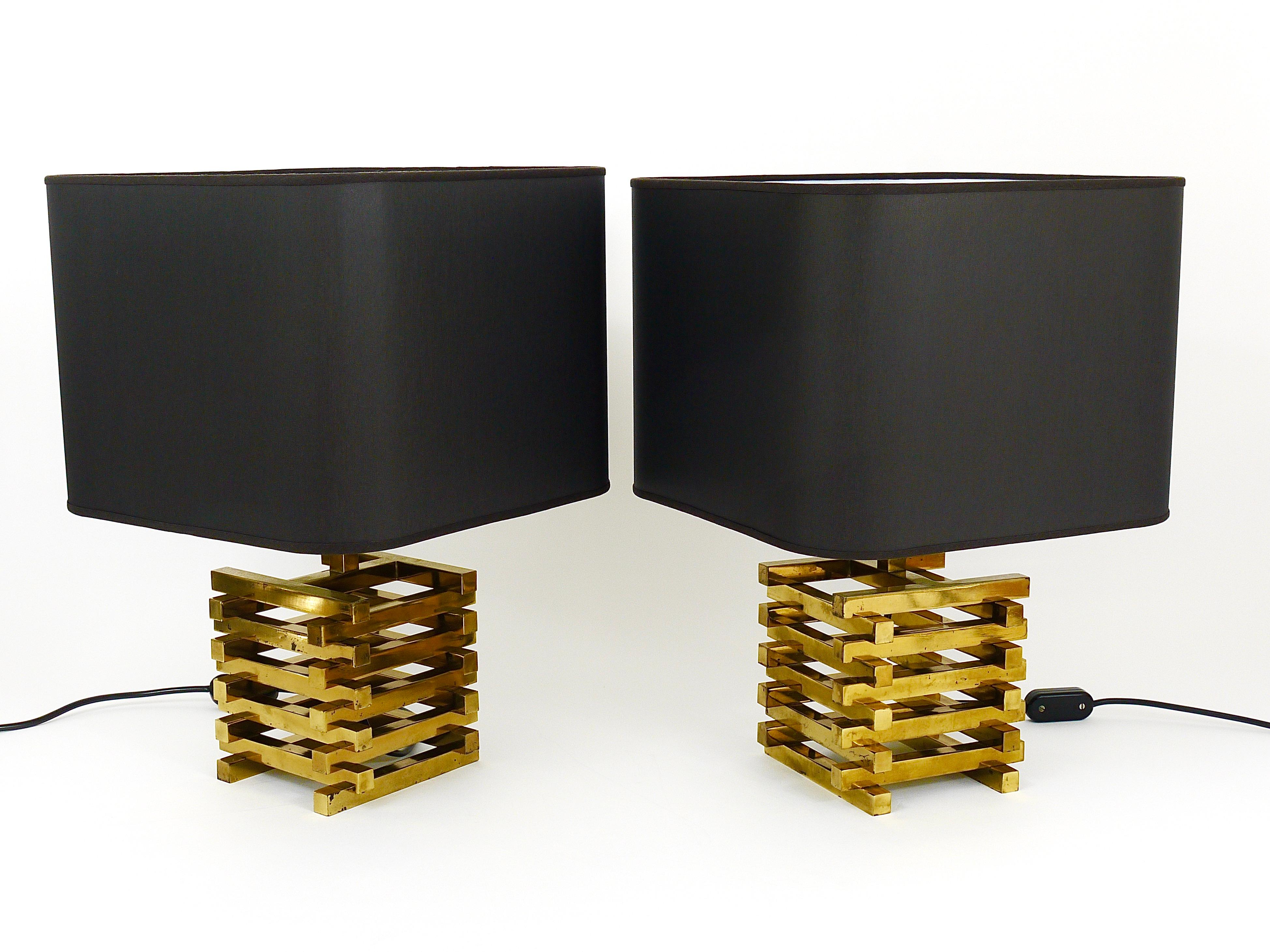 A pair of hollywood regency brass table / side lamps from the 1970s by Romeo Rega, Italy. The lamps consist of beautiful and solid square brass cage bases with black refurbished lampshades. In good condition with charming patina on the brass.