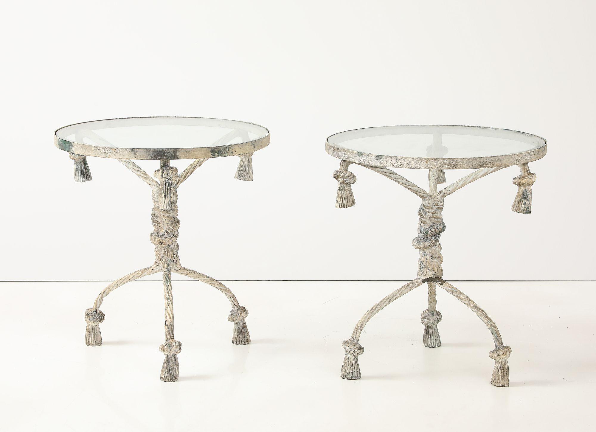 Questa coppia di tavoli rotondi con piano in vetro presenta una base a treppiede in corda ritorta e nappe, realizzata in alluminio fuso verniciato di bianco a metà del XX secolo in Italia. Progettati per essere versatili, questi eleganti tavoli sono