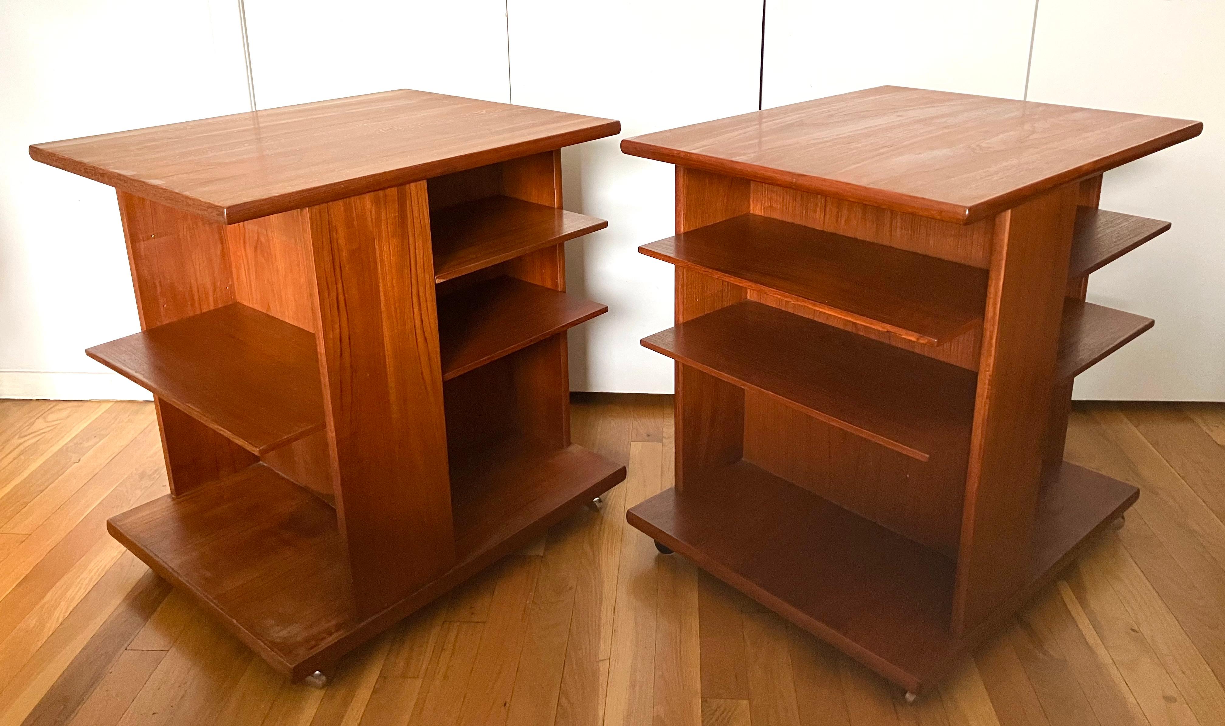 Handsome and masculine pair of Danish Modern rolling bookcase side tables raised on chrome casters. Divided into three shelving sections, each table has two adjustable shelves in two bays and a single adjustable shelf in a third bay.