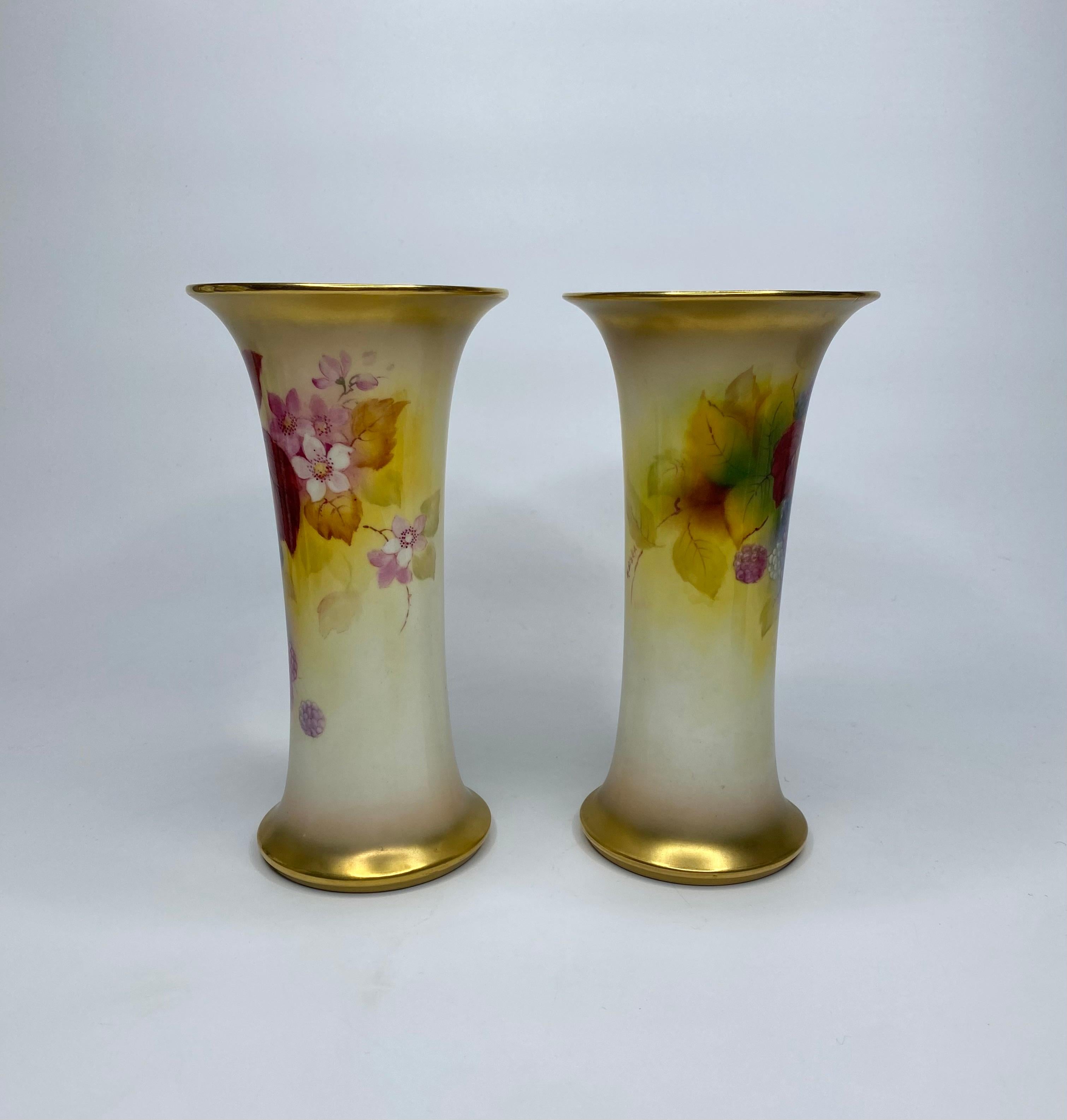 Paire de vases en porcelaine Royal Worcester, signés Kitty Blake, datés de 1936. Les deux vases en forme de trompette sont finement peints avec des études de mûres, parmi des feuilles d'automne et des fleurs, entre des bords dorés.
Signé - K.K.