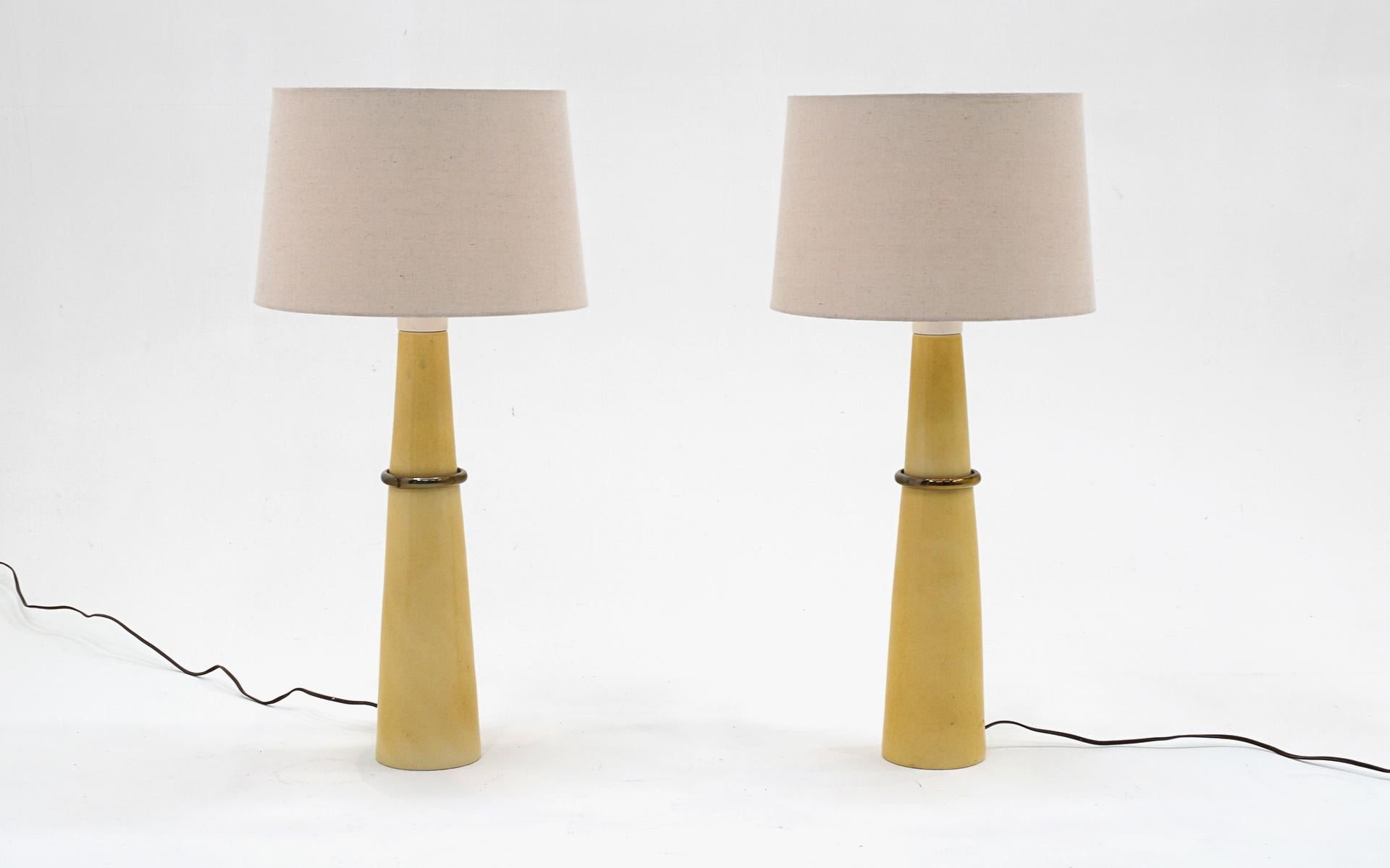 Pair of Russel / Russell Wright table lamps in mustard yellow glazed ceramic with brass ring.  Original round wooden switch.  Very good condition with no chips or significant scratches.  The white painted portion has very small areas of loss on