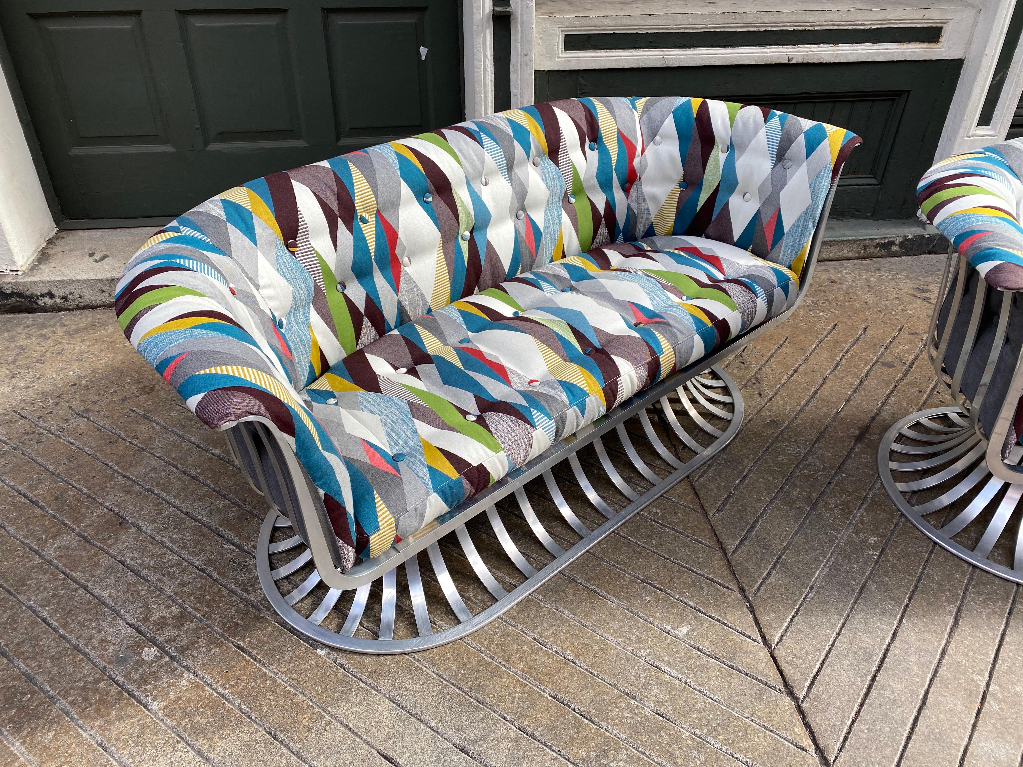 Pair of Russell Woodard aluminum loveseats, newly upholstered in a harlequin fabric in shades of blue, yellow, green and red. Entire series of aluminum furniture designed by the Woodard Furniture Company. Lightweight and easy to move! Very solid and