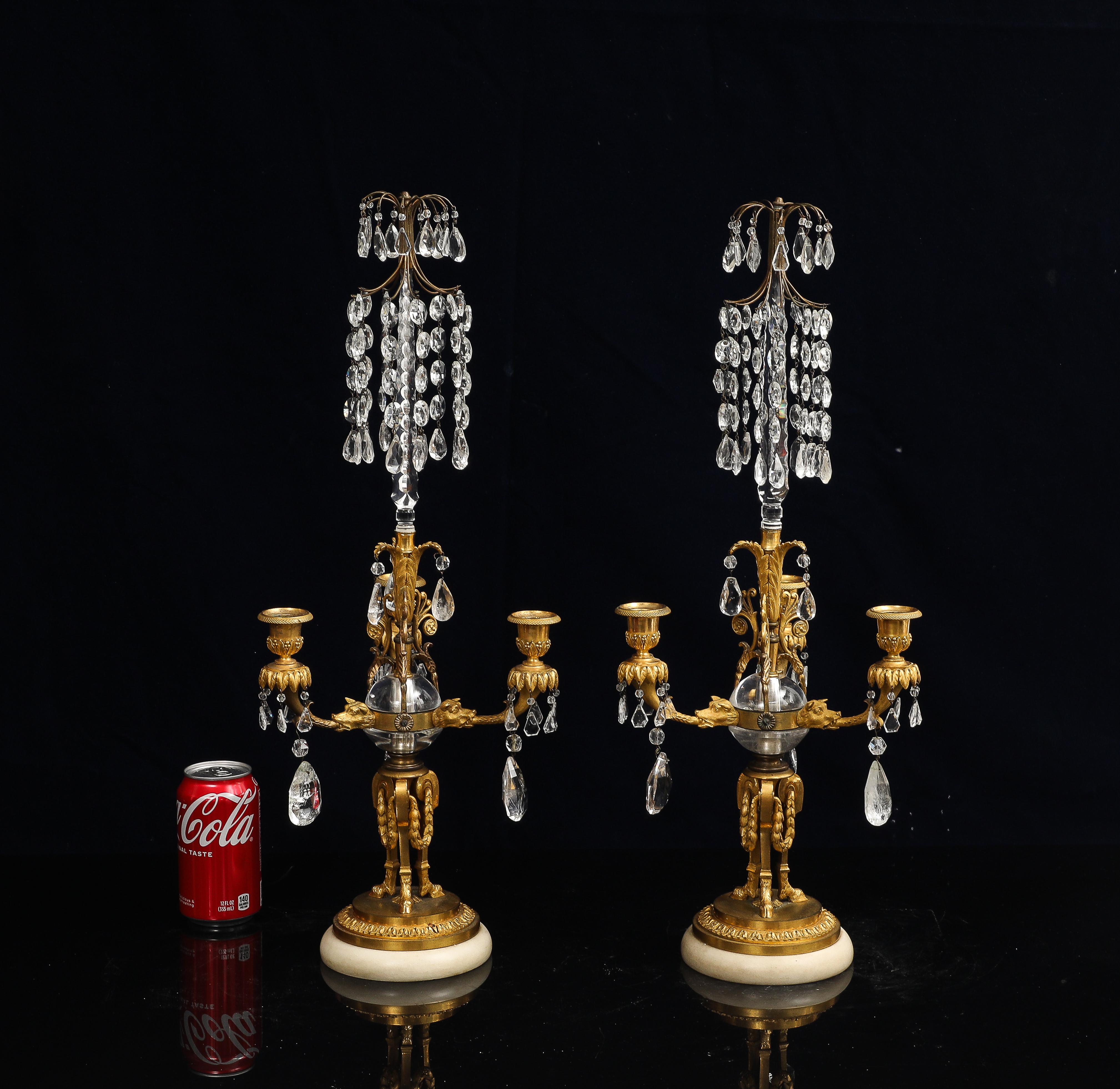 Fantastica coppia di candelabri a tre bracci in bronzo Dore russo del XVIII secolo, cristallo di rocca e marmo con teste di cane. Ogni candelabro poggia su una base circolare in marmo bianco circondata da una fascia in bronzo dorato decorata con un