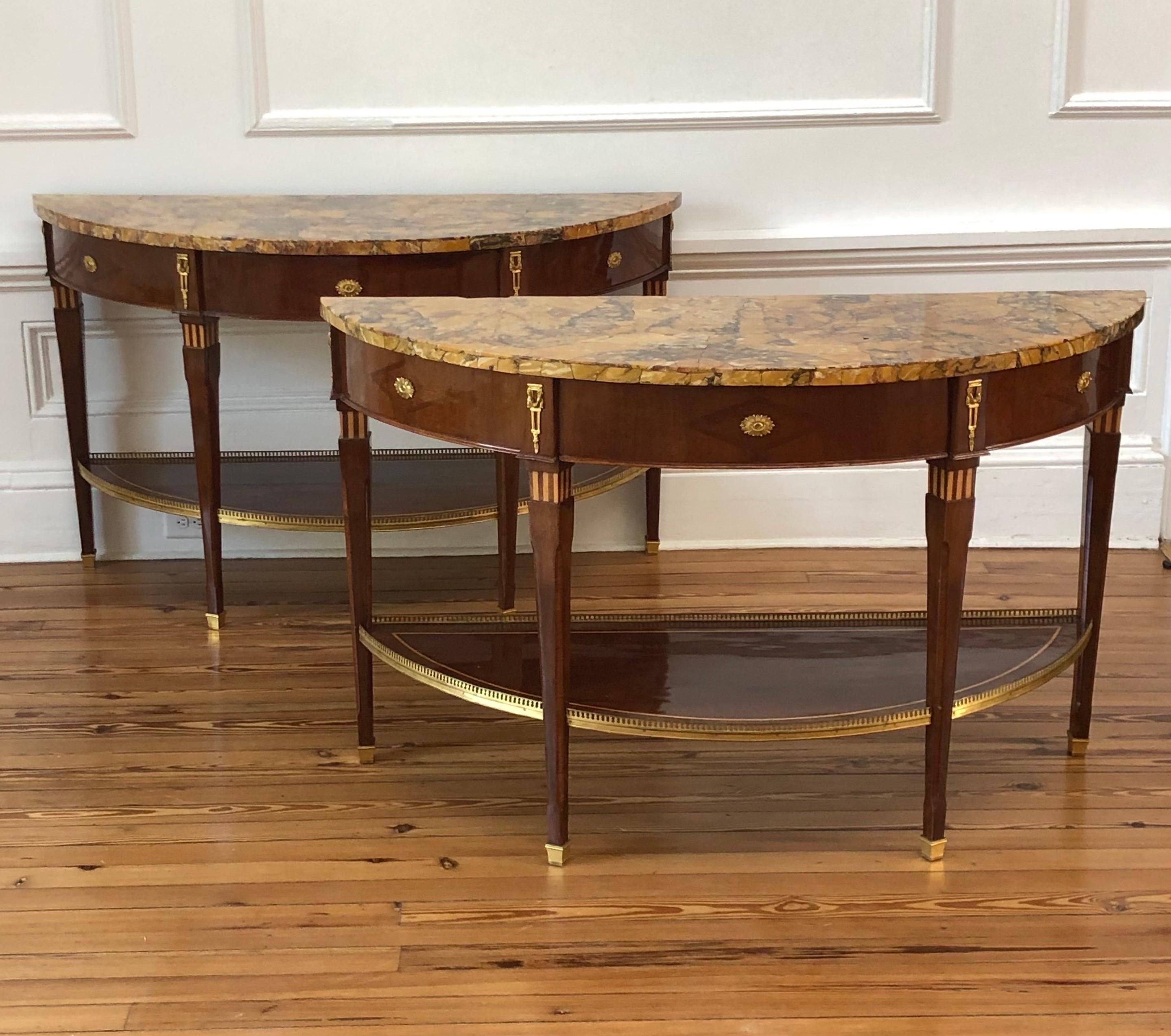 Questa elegante coppia di tavoli da pranzo/console neoclassici russi impiallacciati in marmo di Siena e montati in bronzo dorato è stata realizzata alla fine del XVIII secolo.  Gli squisiti piani in marmo originali, riccamente figurati, sono