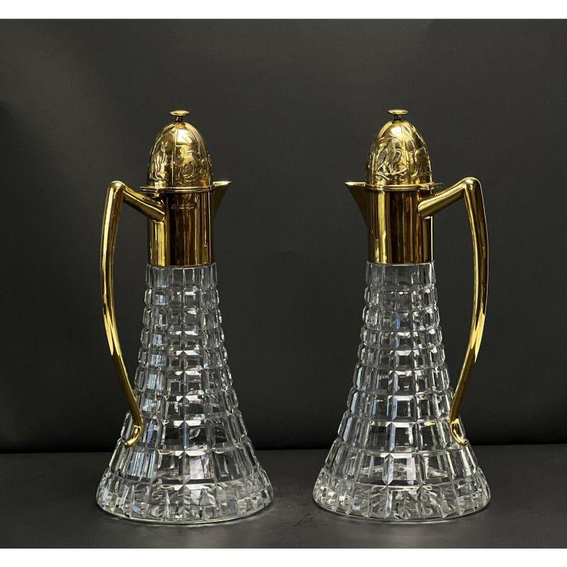 Pair Sarah Jones England gilt sterling silver mounted cut glass Ewers or Carafes

1987. Clear geometric cut glass bases, gilt sterling silver mounts, hinged lid with raised animal decoration. London silver marks to the side and to the underside