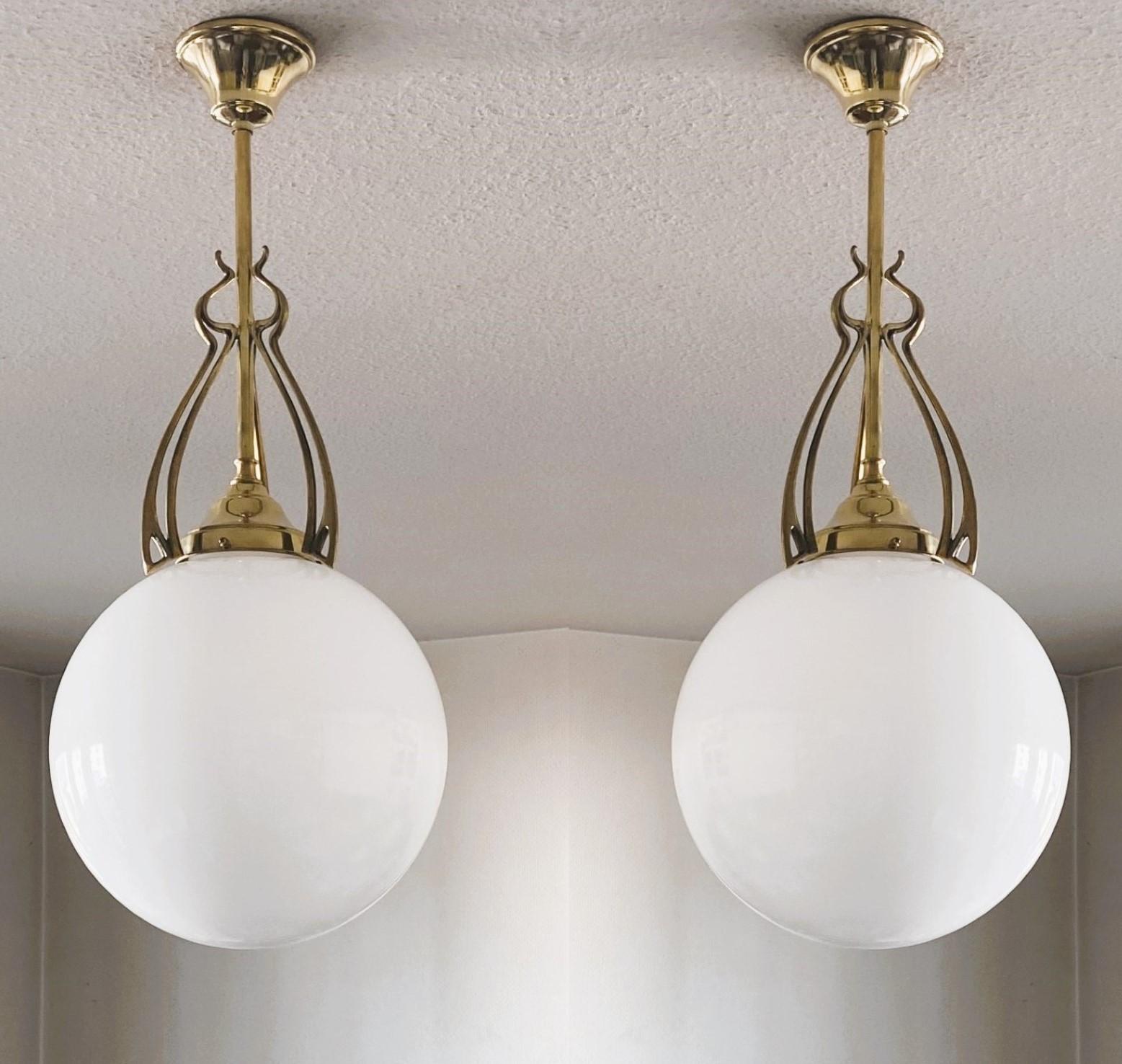 A pair of wonderful and rare ball pendants from the transition period from Art Nouveau to Art Deco, Scandinavia, 1920-1930. Hand-blown opaline glas sphere globes with beautifuly elaborate brass galery.
One porcelain E27 light socket for a large