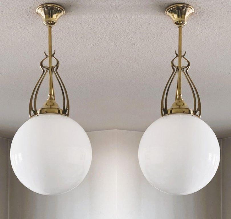 A pair of wonderful and rare ball pendants from the transition period from Art Nouveau to Art Deco, Scandinavia, 1920-1930. Hand-blown opaline glas sphere globes with beautifuly elaborate brass galery.
One porcelain E27 light socket for a large