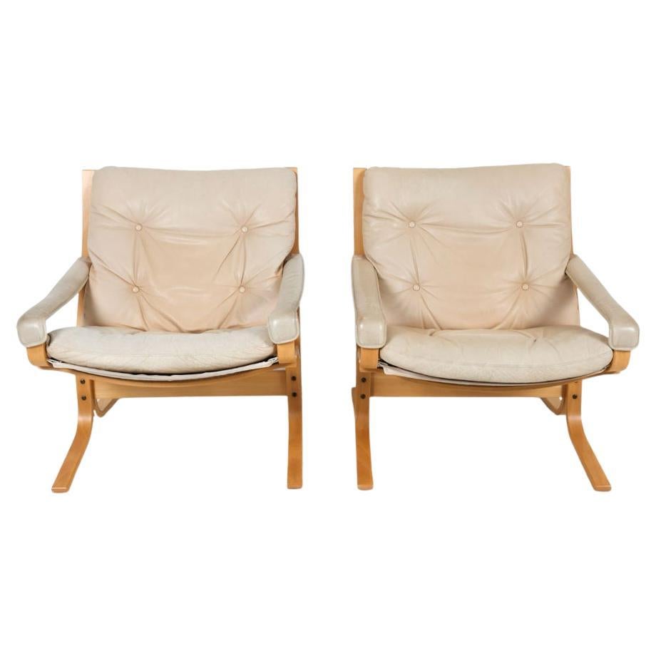Pair of Westnofa Norwegian modern Low Siesta Safari chairs designed by Ingmar Relling. Blonde beech Beech Wooden frames, beautiful light beige leather cushions. Bentwood frames and tan cloth sling backing. Westnofa Furniture label to underside