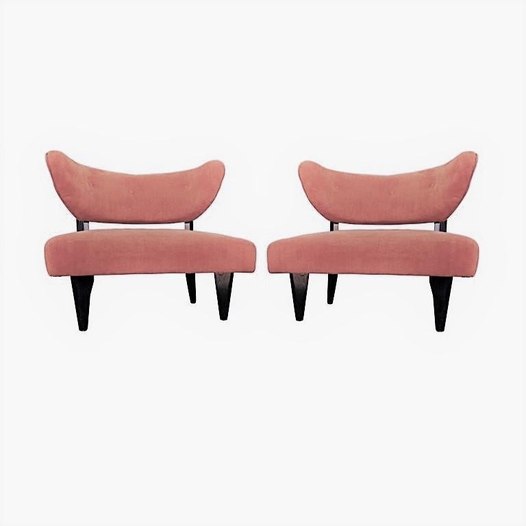 Beautiful pair of wide Art Deco club / lounge chairs. Its sensual curves and distinctive sharp tapered legs give the chairs a sculptural and modern feel. These sumptuous armchairs have been fully reconditioned and newly upholstered in a light rose