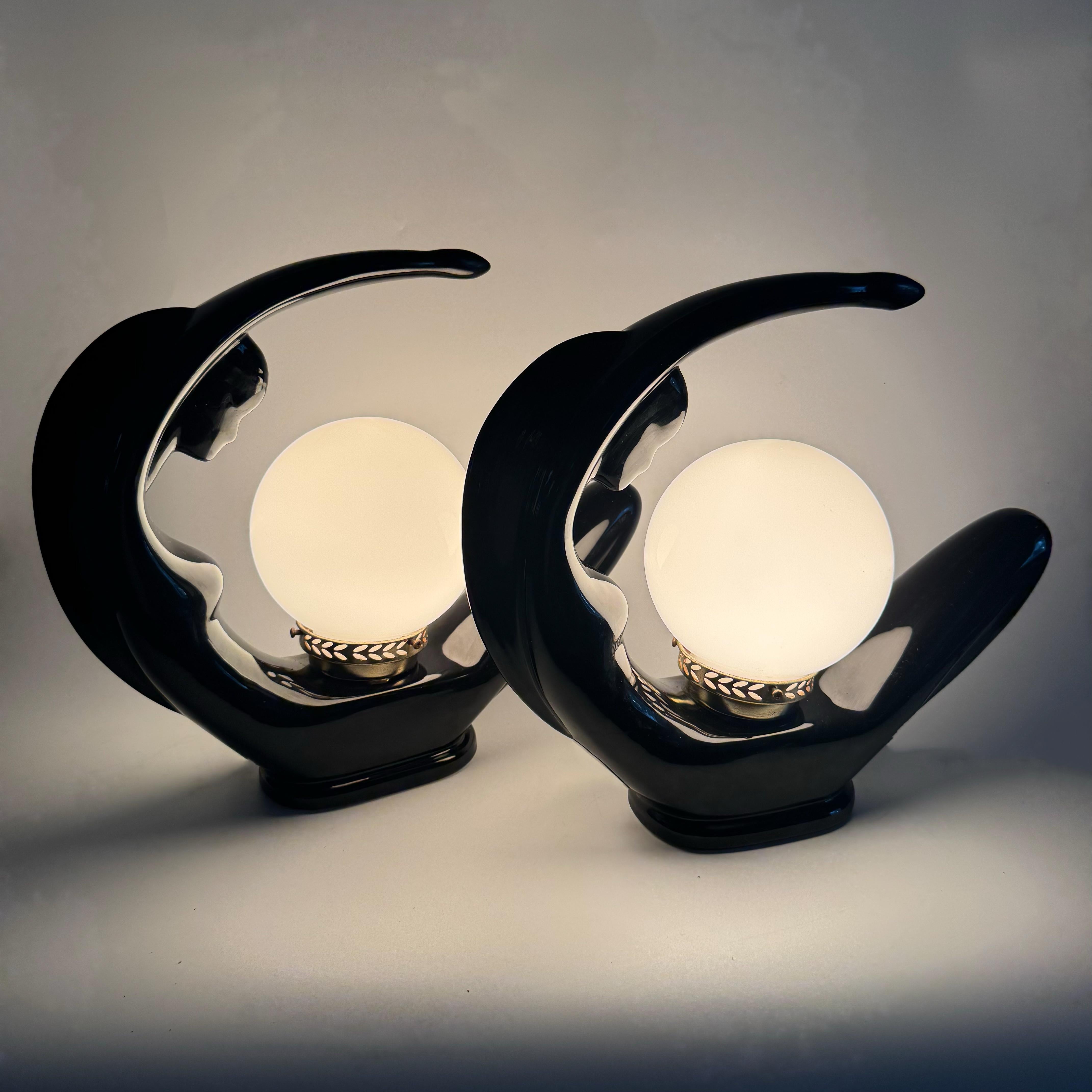 Une paire rare et spectaculaire de lampes de table en céramique des années 1980 représentant des silhouettes féminines stylisées dans des poses dynamiques et courbes. Finie dans une riche glaçure noire brillante, chaque figure est entourée d'un