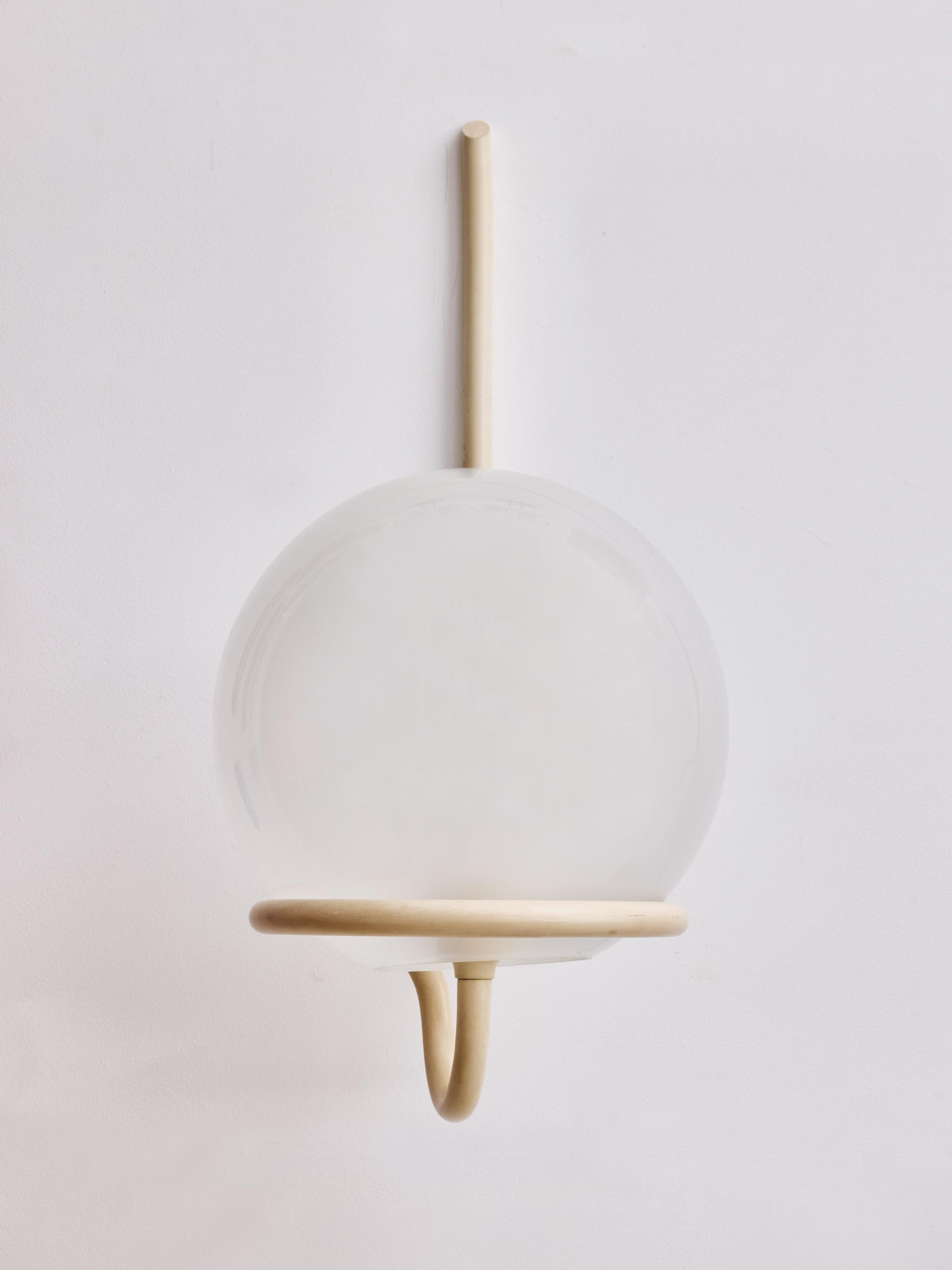 Eleganti e sobrie applique da parete disegnate da Sergio Asti per Arteluce, modello 145, prodotte in Italia negli anni '60. Il design è caratterizzato da un grande globo di vetro opalino soffiato a mano che poggia su una scultorea struttura in