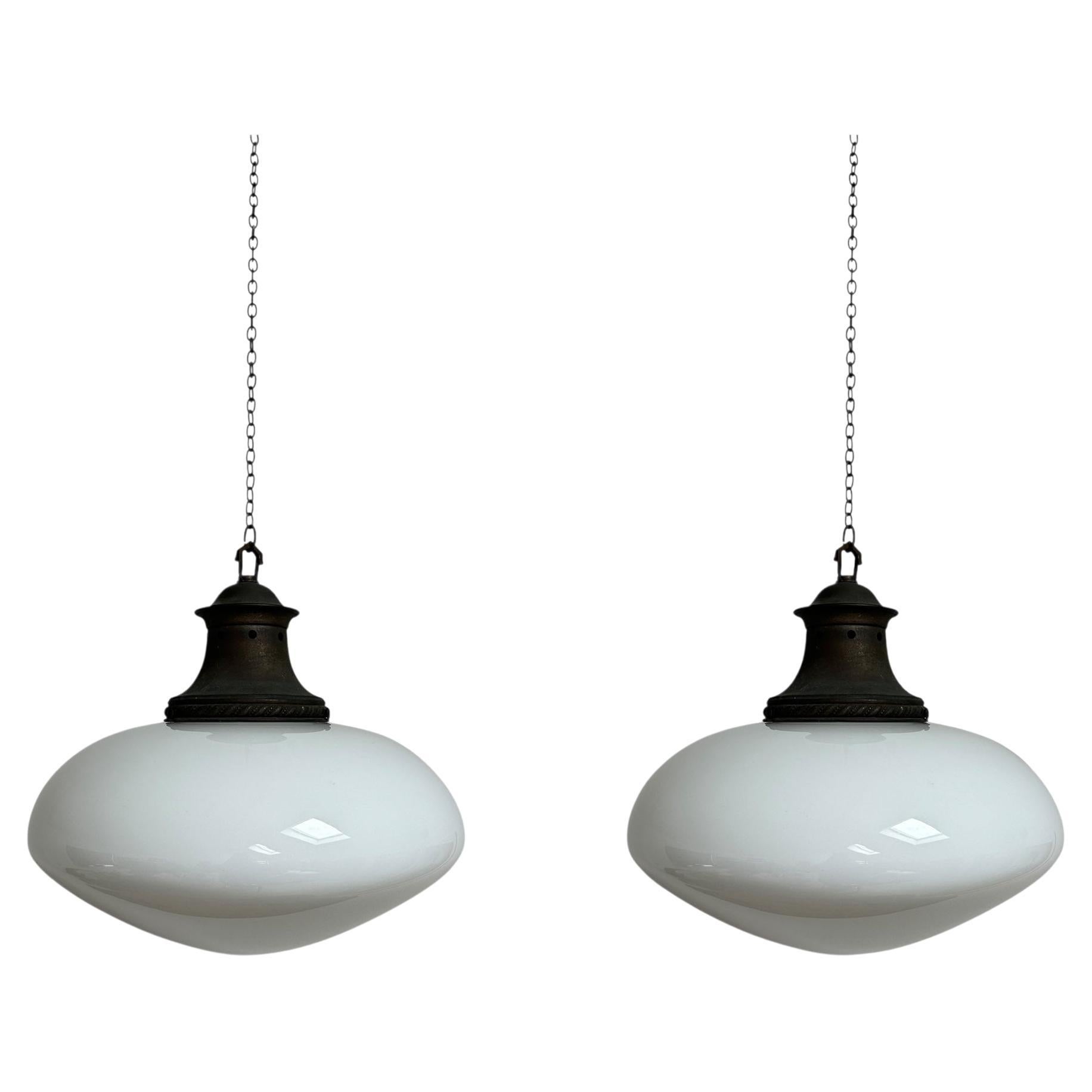 - A matching pair of extra large oval lid opaline glass ceiling pendants with heavily patinated galleries, England circa 1920.
- Incredible eye catching shape with beautiful white opaline glass, wear commensurate of age, both in wonderful heavily