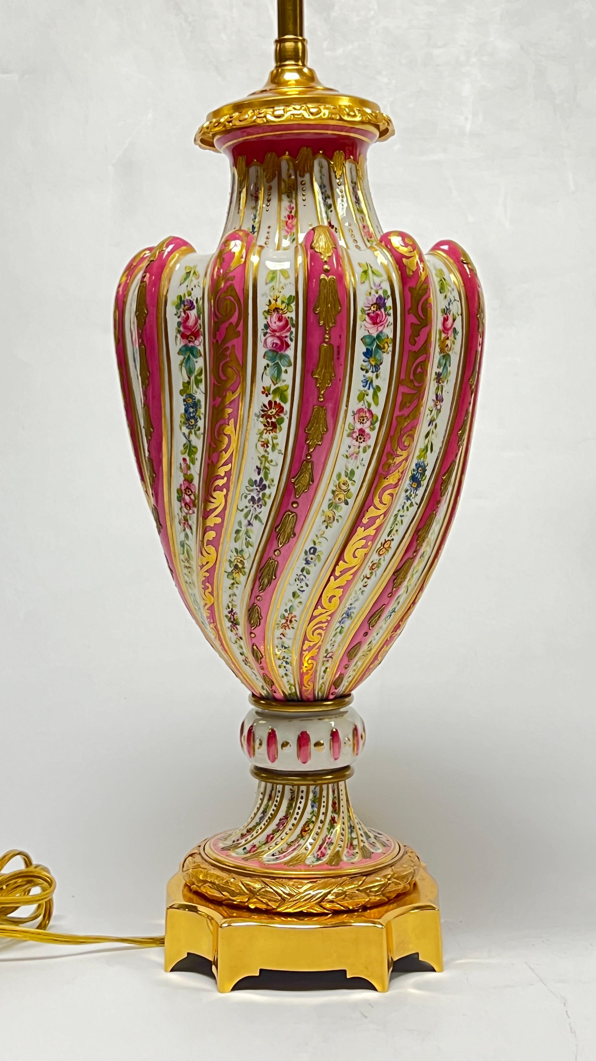 Notre paire de lampes de table anciennes en porcelaine avec des montures en bronze finement moulées, dorées et polies, au motif de la Rose Pompadour de Sèvres, date du premier quart du 20e siècle et est en excellent état. Marqué Made in France sur