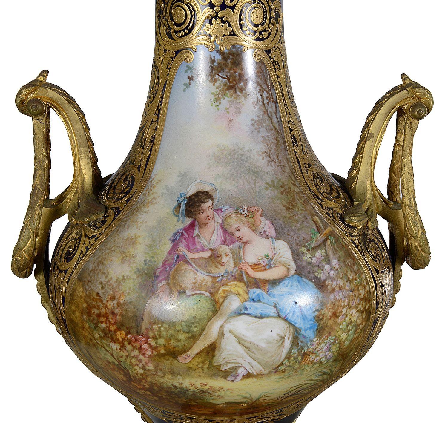 A pair of19th-century Sèvres style vases featuring an elegant urn shape with a flared lip and sturdy base. The cobalt blue colour is a beautifully contrast to the intricate gold embellishments, showcasing exquisite craftsmanship. Each vase is