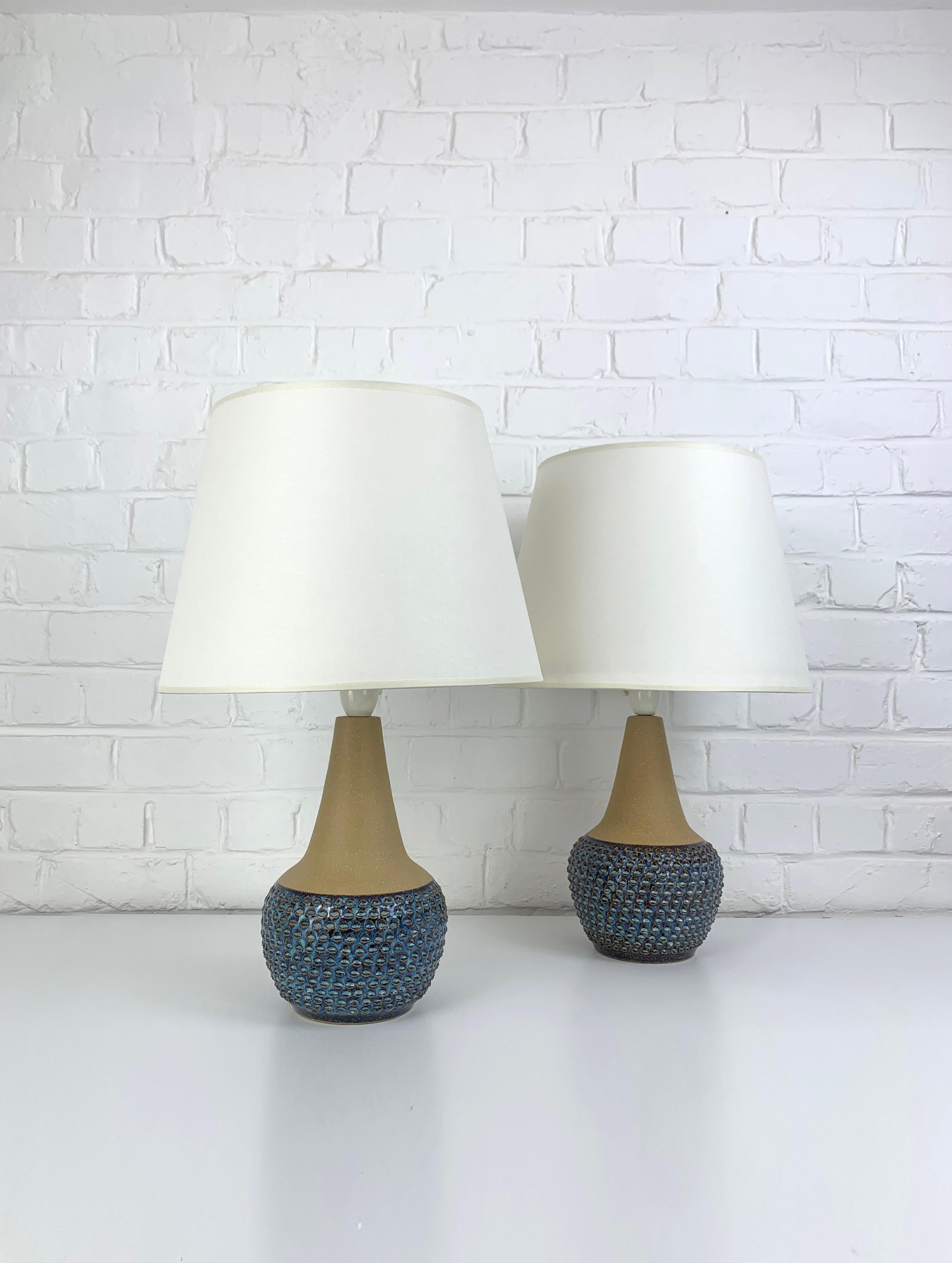 Coppia di grandi lampade da tavolo danesi del Mid-Century in gres degli anni 1960-70.   

La parte inferiore delle lampade è decorata con un motivo impresso, smaltato in blu scuro e chiaro con accenti ocra. La parte superiore non è smaltata e mostra