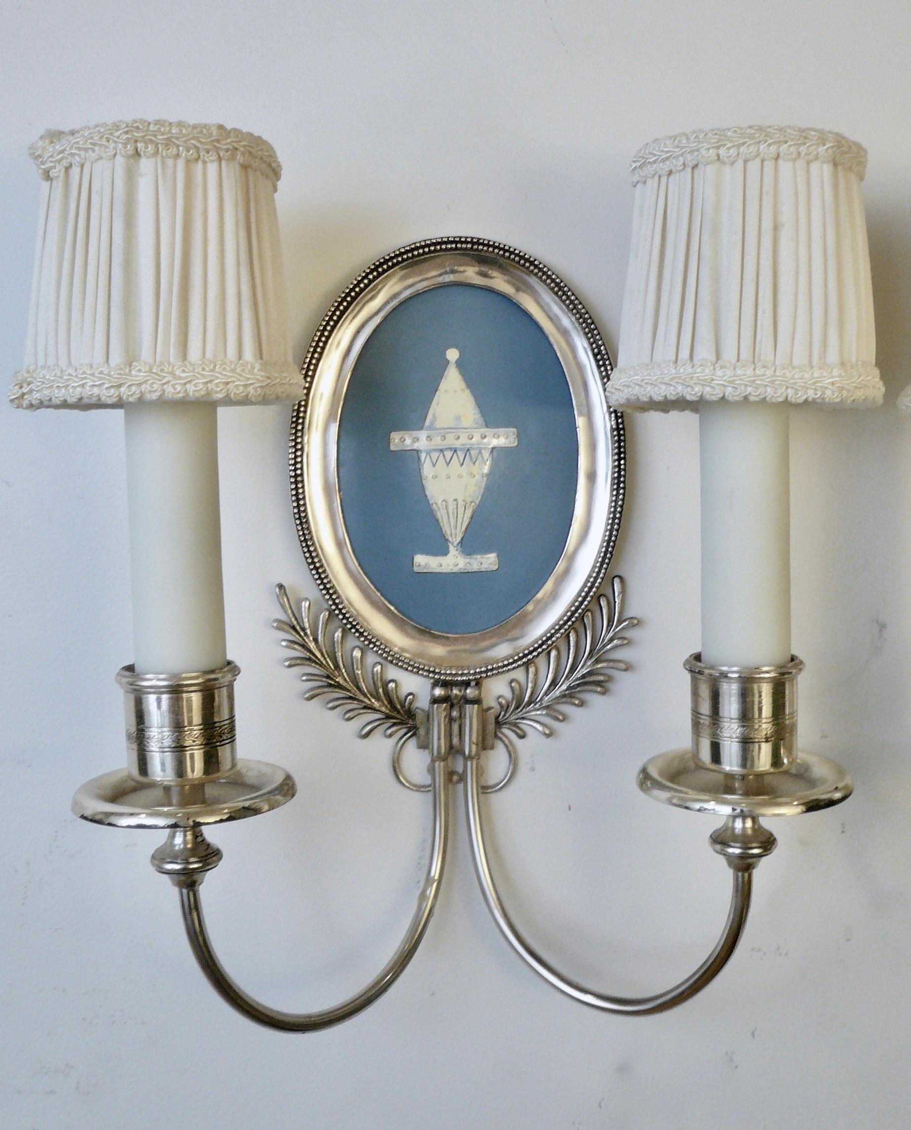 This beautiful pair of signed sconces by renown maker Edward F. Caldwell feature oval Battersea type enamel on copper reserves decorated with neoclassical style urns. The silver plating is original and in excellent condition.
 