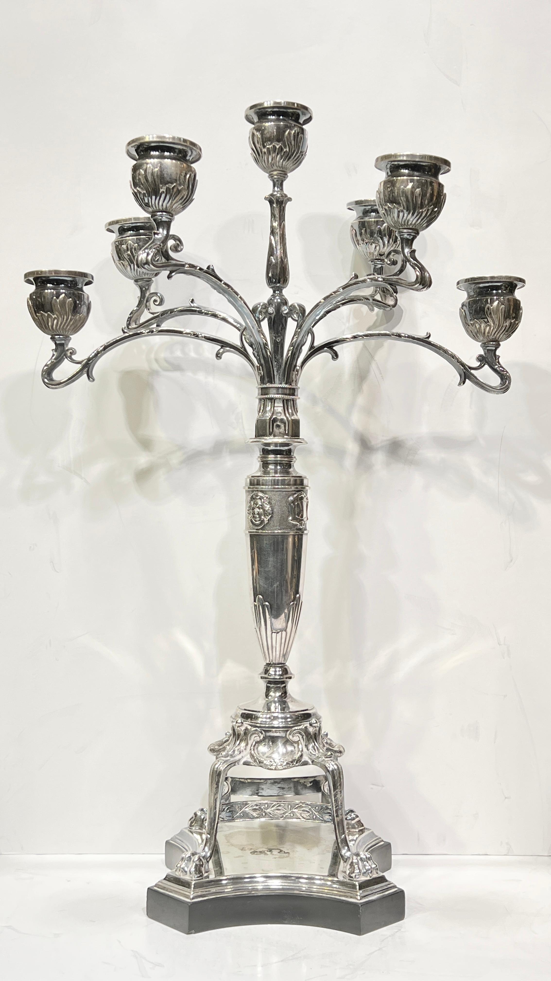 Pair of silvered bronze five-light candelabra with polished black marble bases in the renaissance style, each 23 by 15 by 9 inches, the standard with male and female masks, raised on footed base with lion paw feet and mounted to polished black
