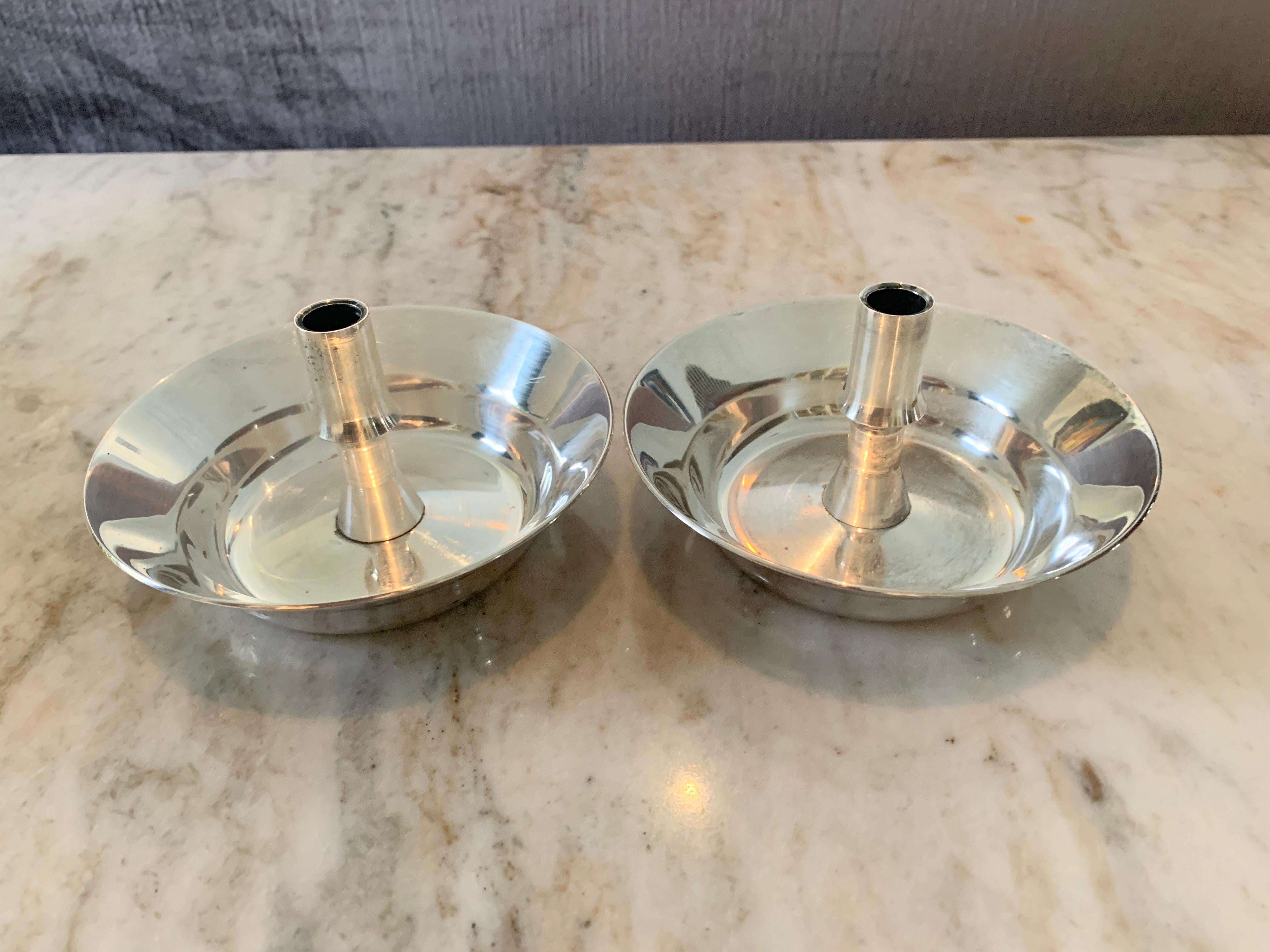 Midcentury sleek, architectural Danish design by Jens H Quistgaard and produced by Dansk Designs Copenhagen. Pair of silver-plate ‘saucer’ candle holders, the pair can easily work in both casual and formal settings, Dansk Designs Denmark IHQ.
 