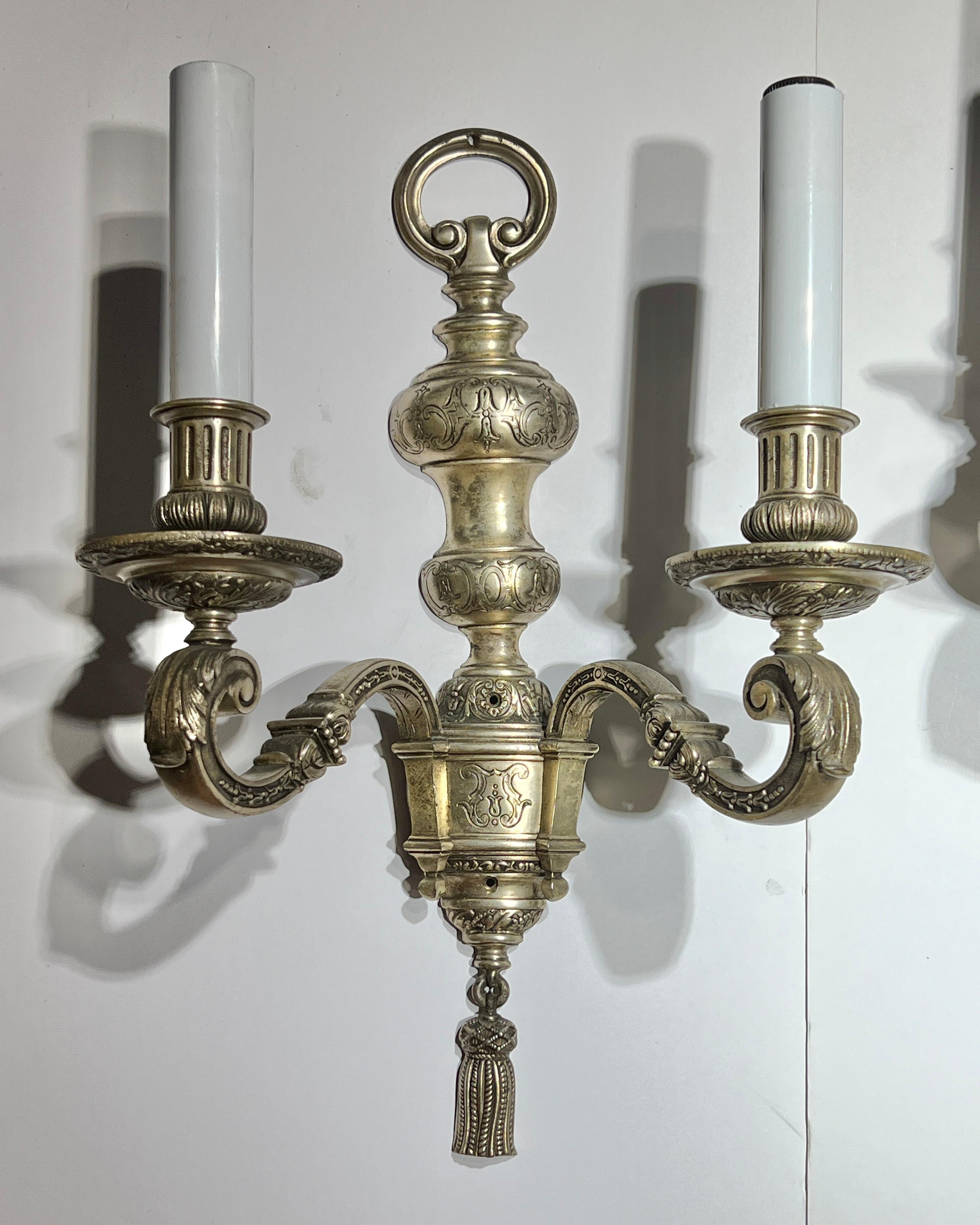 Coppia di antiche appliques a 2 luci in metallo argentato (inizio XX secolo), attribuite a
Edward F. Caldwell, misura 18 x 14 x 6 pollici, con le prese originali per candelabri in porcellana bianca. 