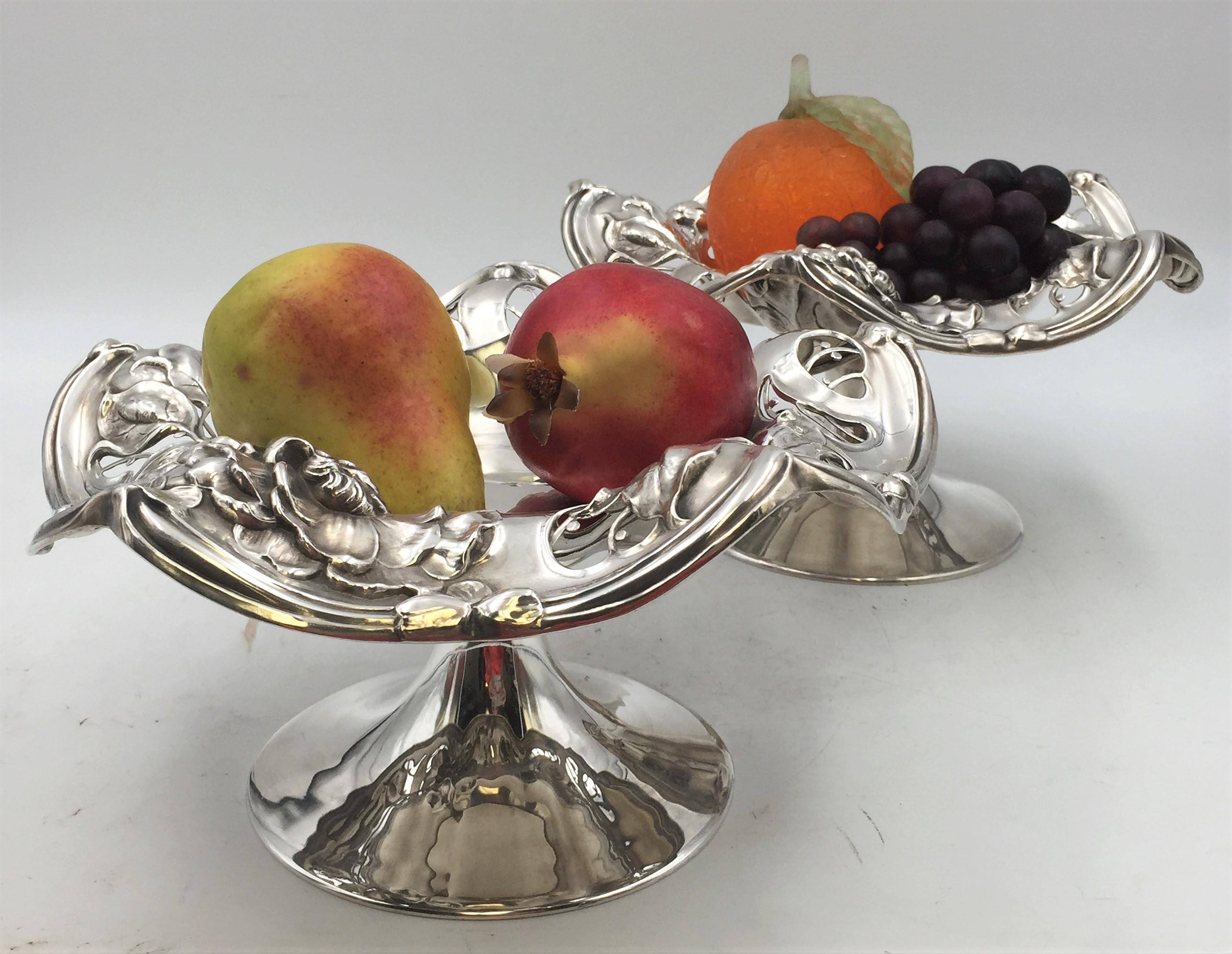 Early 20th century pair of Simpson, Hall, Miller & Co. sterling silver compotes / footed centerpiece bowls in exquisite Art Nouveau style with pierced work and raised floral motifs, in a riveting, twirling shape. They measure 10'' in diameter by 5
