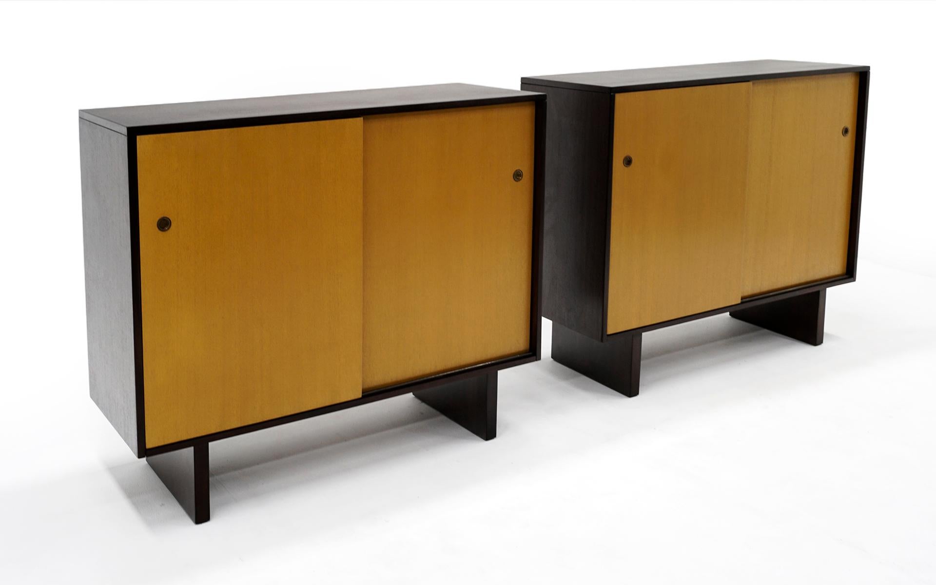 Rare and fine pair of dressers / chests / storage cabinets designed by T.H. Robsjohn-Gibbings for the John Widdicomb Company, 1950s. The mahogany cases have been expertly refinished in the original dark top and sides, bleached fronts with brass