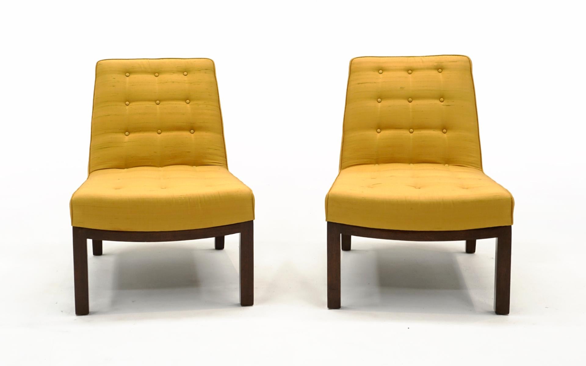 Beautiful and elegant pair of armless slipper / lounge chairs designed by Edward Wormley for Dunbar. These are in completely original condition: original yellow silk fabric and original dark finish on the mahogany legs. No stains, tears or repairs.