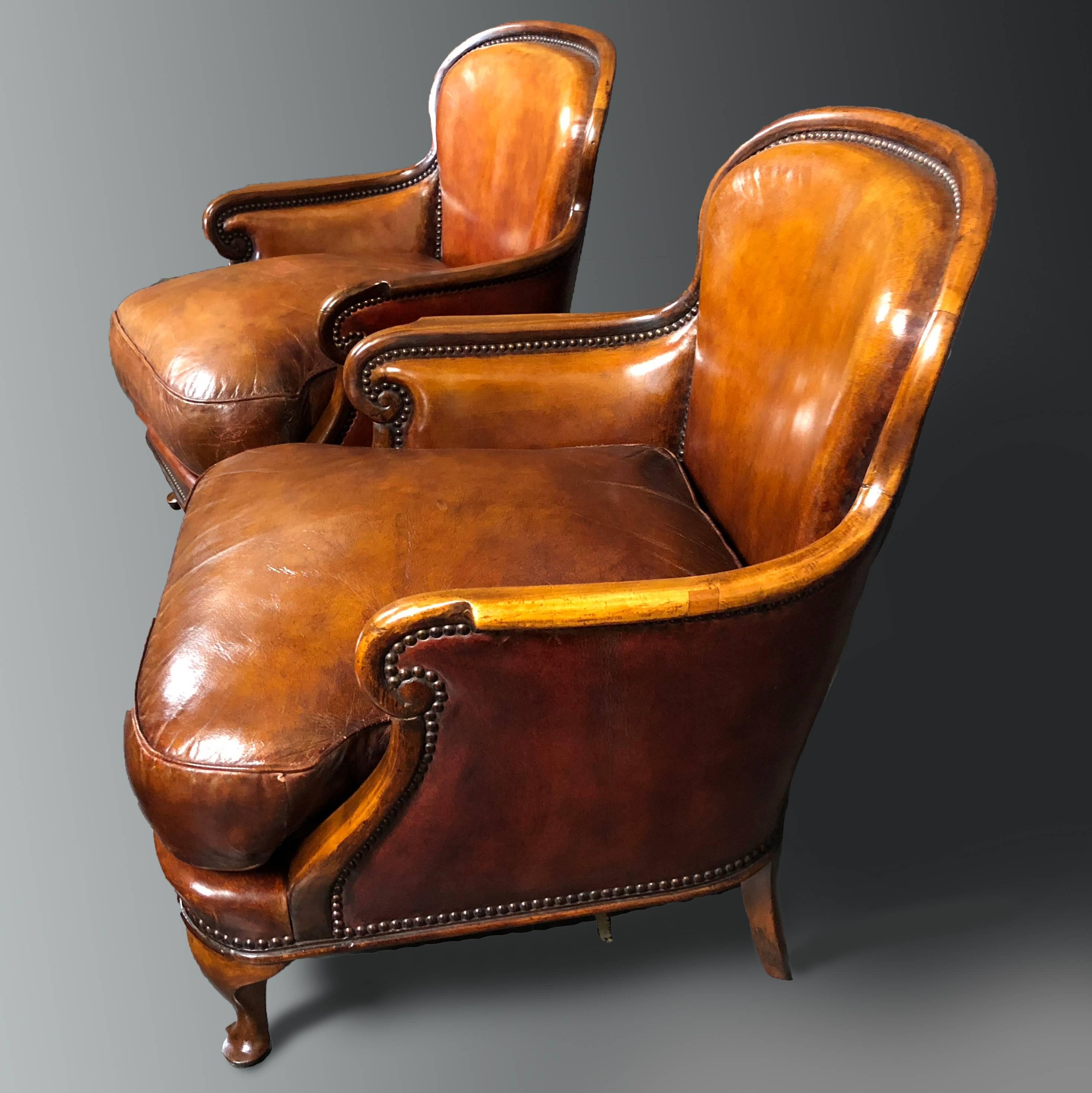Attractive pair of small English antique leather armchairs on walnut frames with Queen Anne style cabriole legs. The pair dates to the end of 19th century and it is whisky brown color with fine patina and studs. The color of the leather at the sides