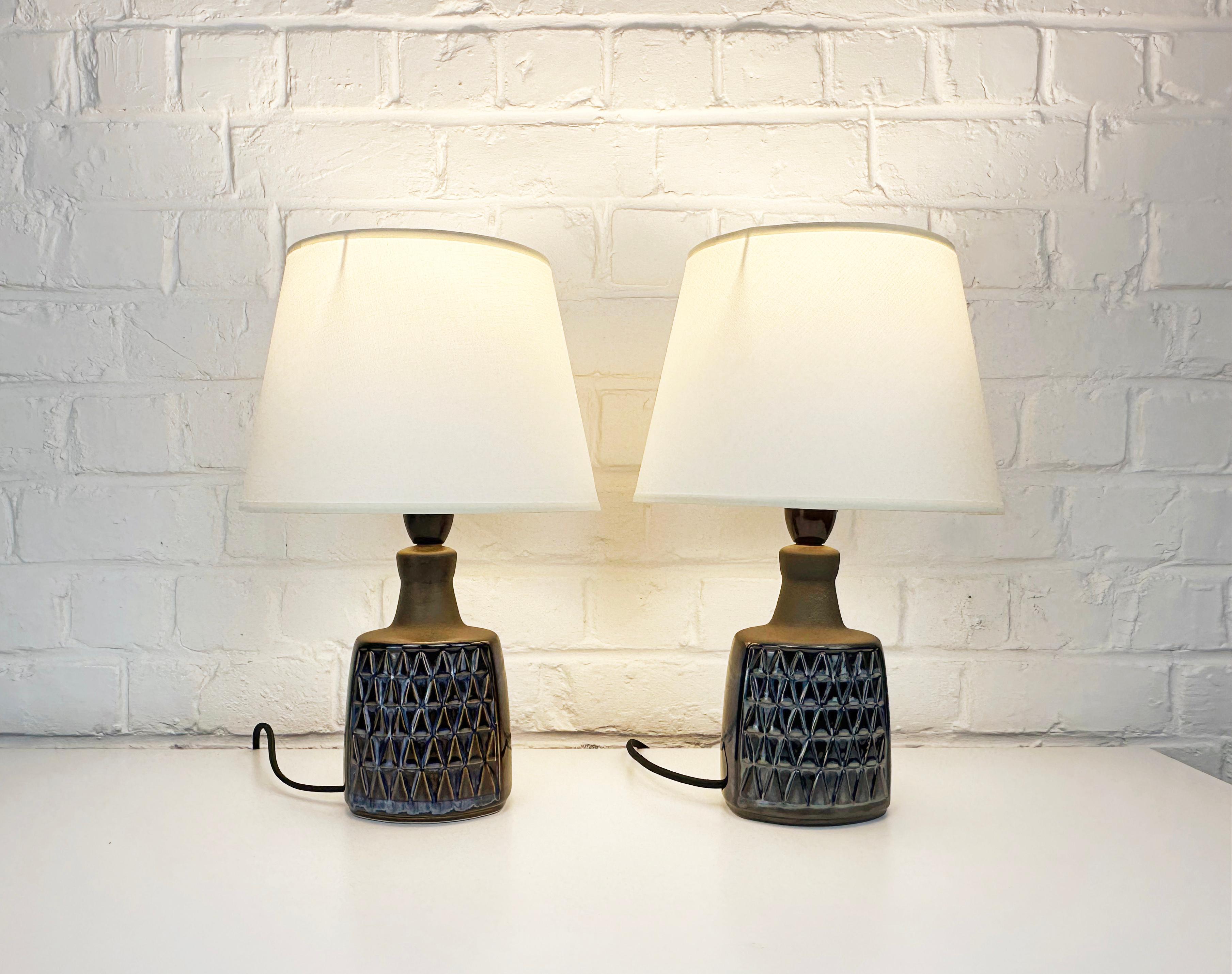 Pair of small Mid-Century ceramic table lamps, perfect as nightstand lamps. 

Dark blue glazed geometric triangle-pattern with light blue and brownish accents. The upper part of the lamps is not glazed and comes in a very dark brown tone.

Model