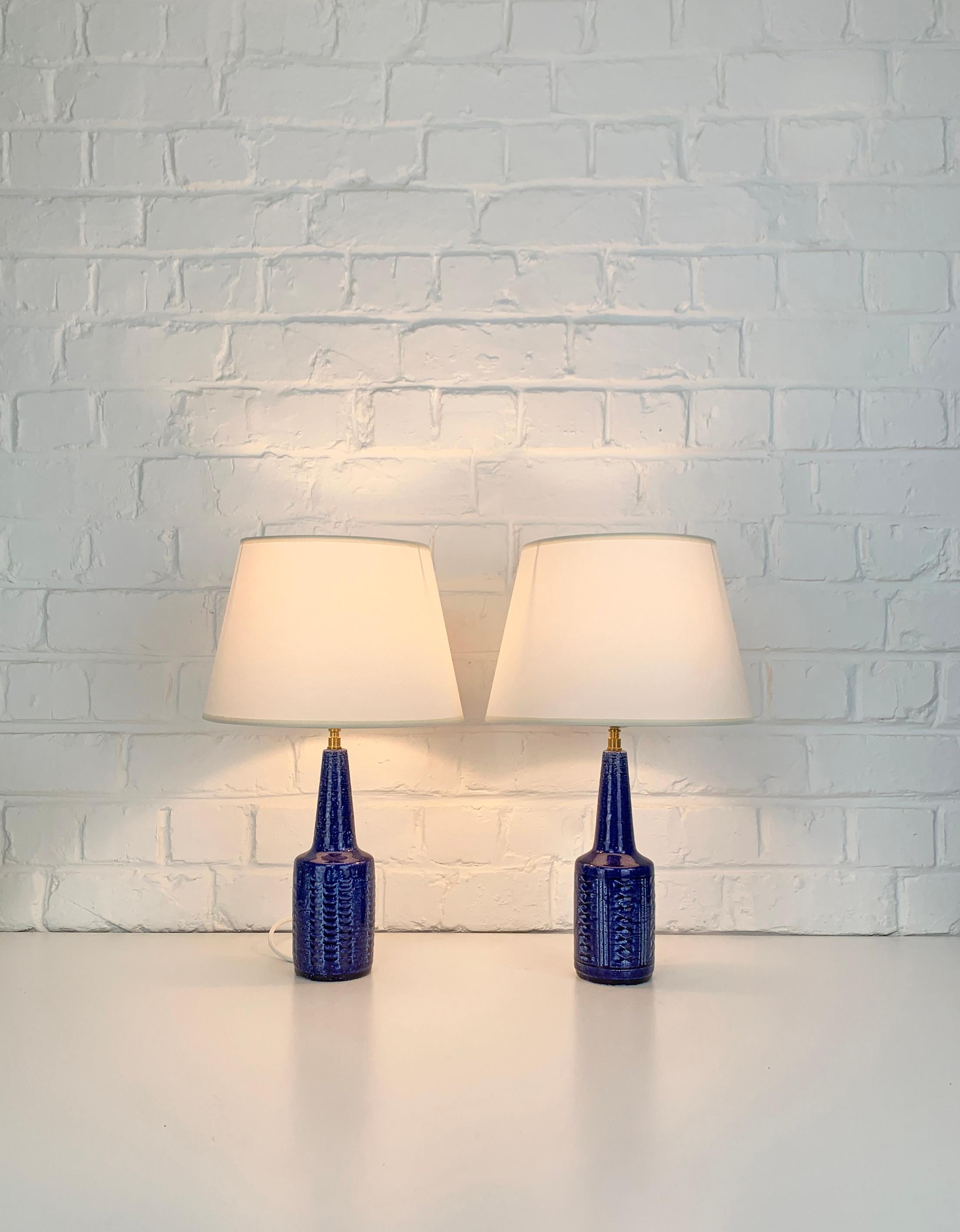 Pair small stoneware table lamps, model DL29, produced by Palshus (Denmark). 

The lamp bases are finished with a blue glaze and impressed pattern. The chamotte clay gives a natural and living surface. Both are signed under the base (PLS for Per