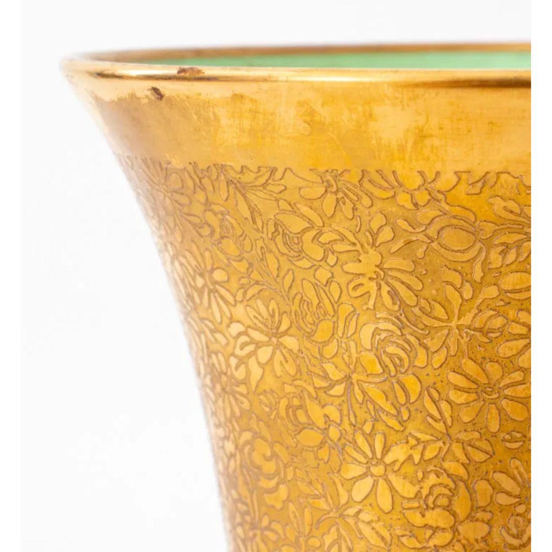 This pair of Campagna urns exudes understated elegance with their small, gold-toned exteriors and intricate craftsmanship. The urns feature a rich, glazed gold finish, with a contrasting green-glazed interior that adds depth and visual interest. The