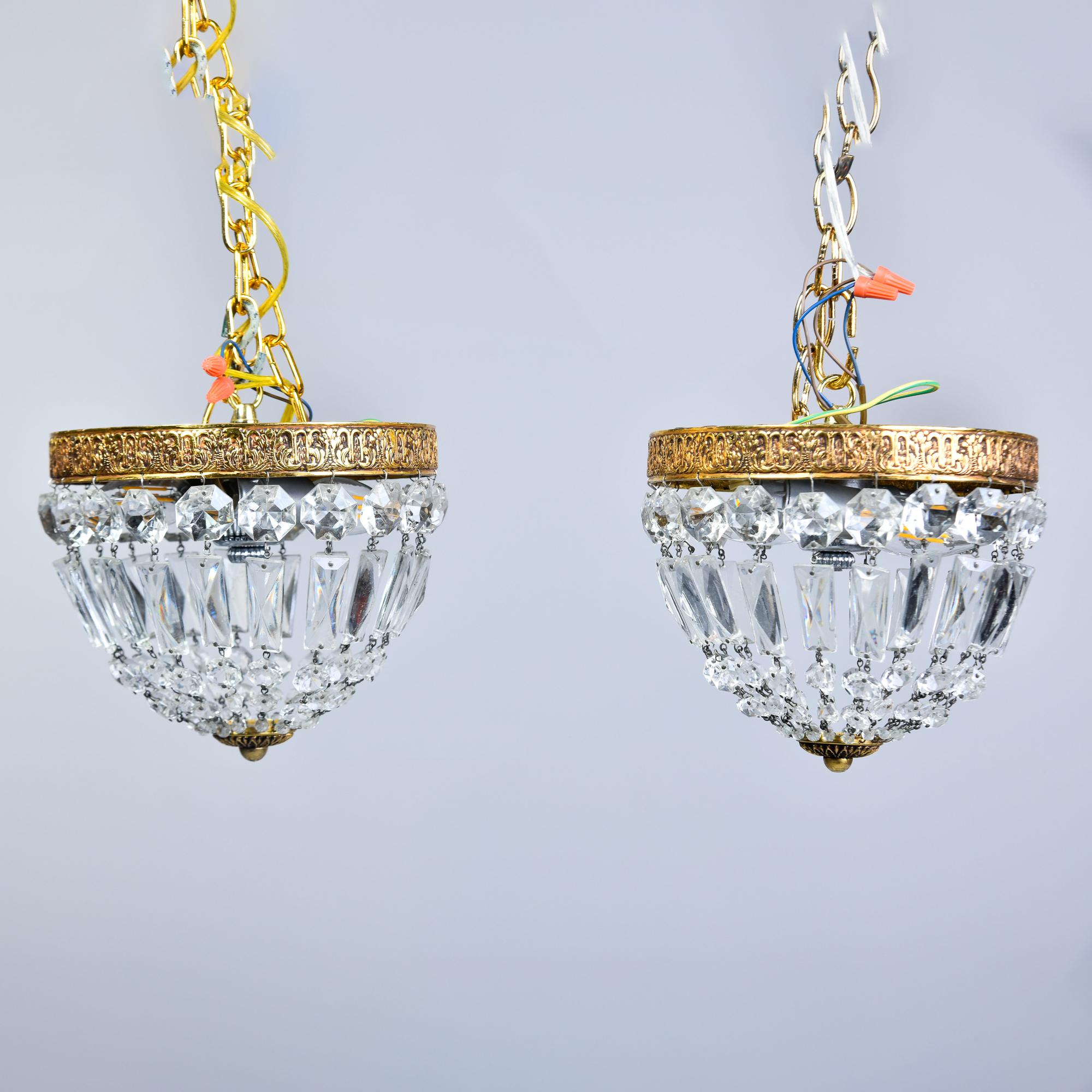 Found in Italy, this pair of small crystal and brass ceiling fixtures date from the 1940s. Stamped brass frames support crystals strung in a basket form with two internal light sockets. Perfect petite fixtures for a powder room, alcove or hallway.