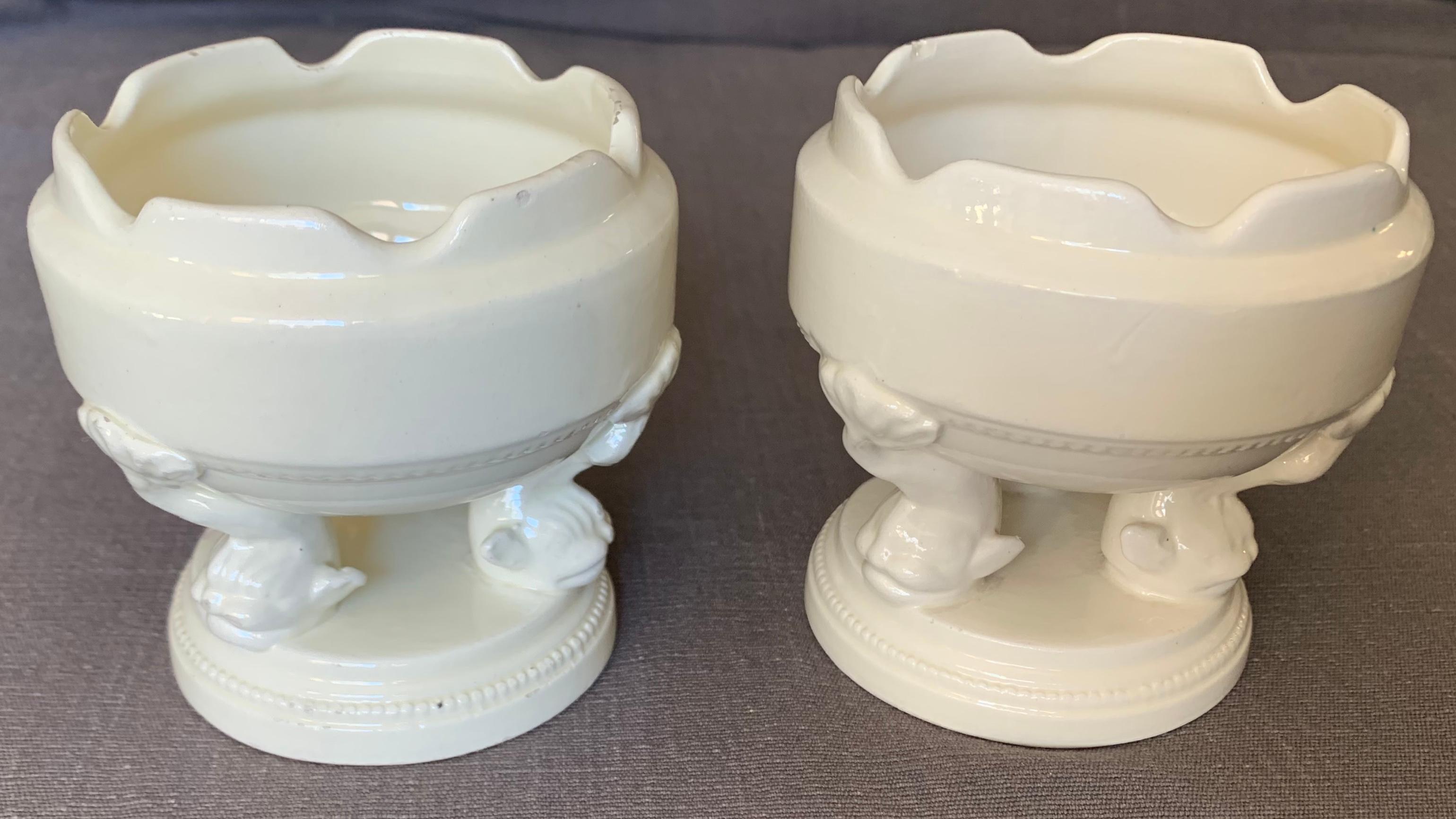 Paire de petits bols en forme de dauphin blanc. Paire d'anciens bols / vases à bourgeons miniatures en faïence crémeuse italienne reposant sur des pieds tripodes en forme de dauphin et sur une base circulaire à gradins conforme ; fabrication