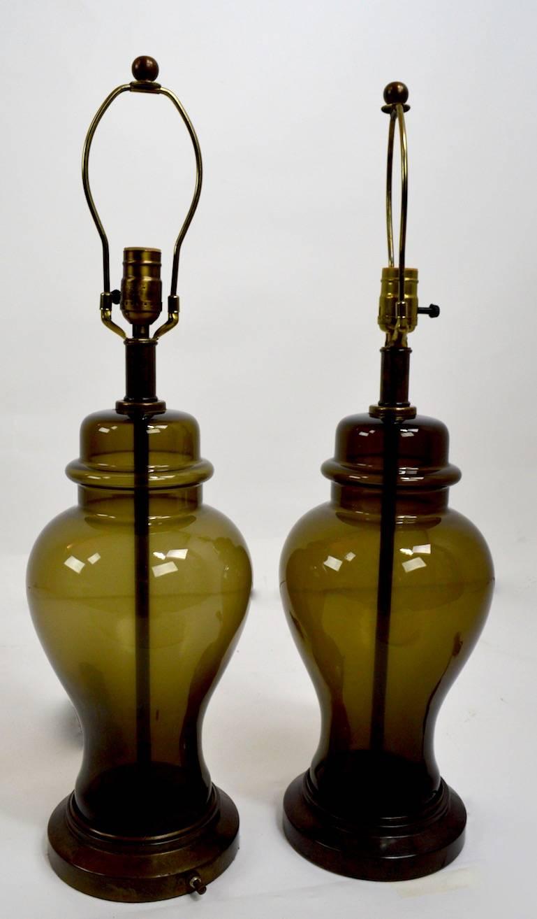 Stylish and chic smoked glass table lamps. Both are in clean, original and working condition. Height to top of glass element 16 inches, shades not included.