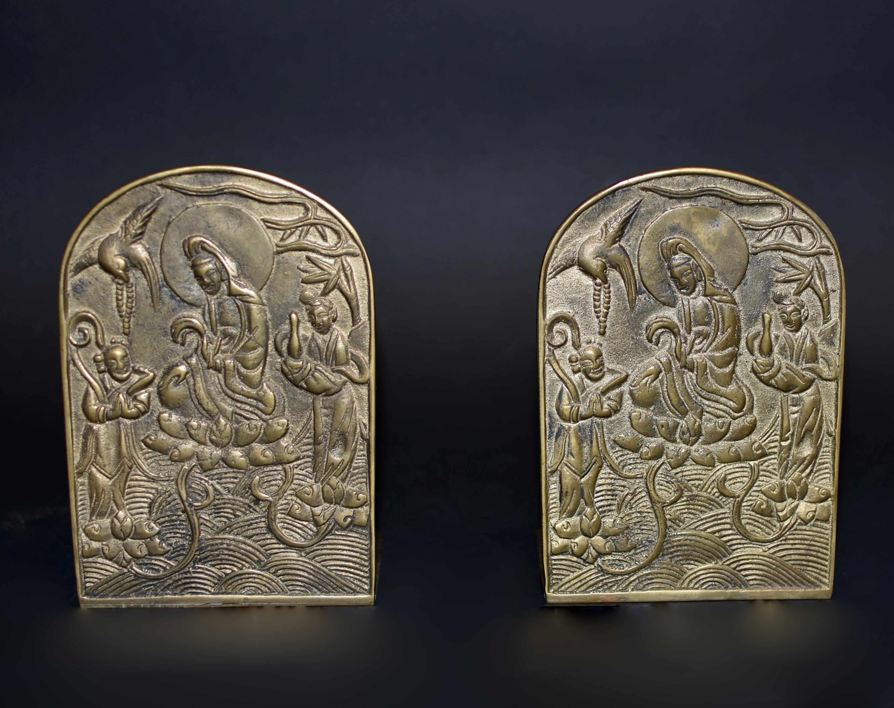 A pair of solid brass bookends depict Guan Yin, Goddess of Great Compassion. Seated on lotus throne, holding a willow branch, Guan Yin is in the action of providing blessings. A female disciple to her left holds a bottle that contains holy water. A