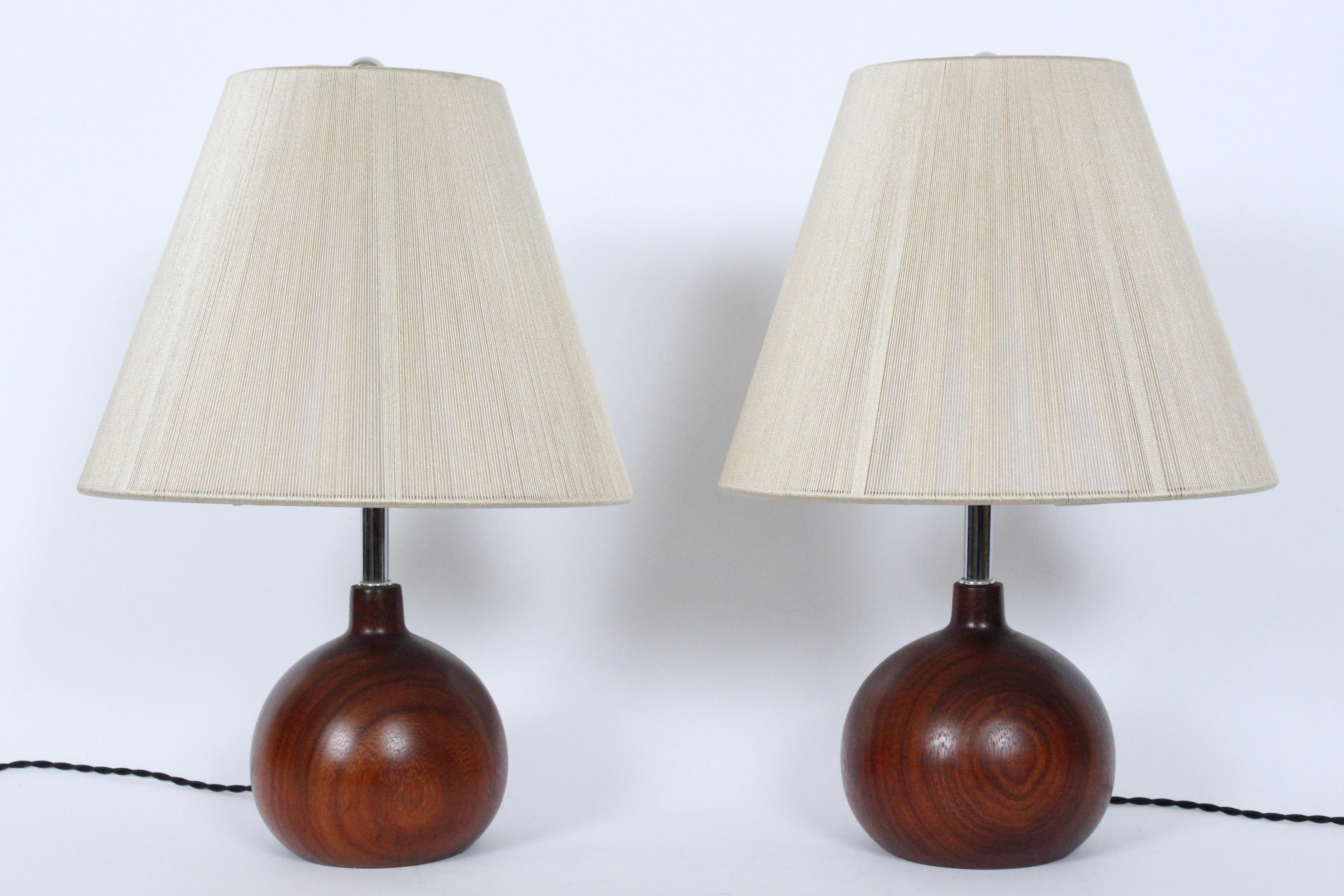 Pair of Danish Modern ESA style dark solid teak table lamps, 1970's. Featuring finely grained, staved Dark Teak globe forms with tubular Chrome stems. 10.5 H to top of Socket. 6H to top of Wood. Shades shown for display only ( 9.5H x 6D top x 12D