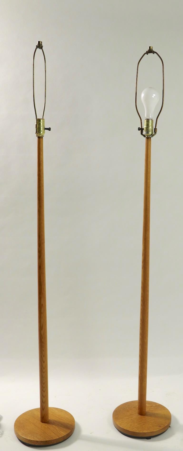 Very chic pair of solid oak pole lamps marked made in Sweden. Midcentury Danish modern style floor lamps in unusually clean condition, working and ready to use. Priced and offered as a pair - shades not included.