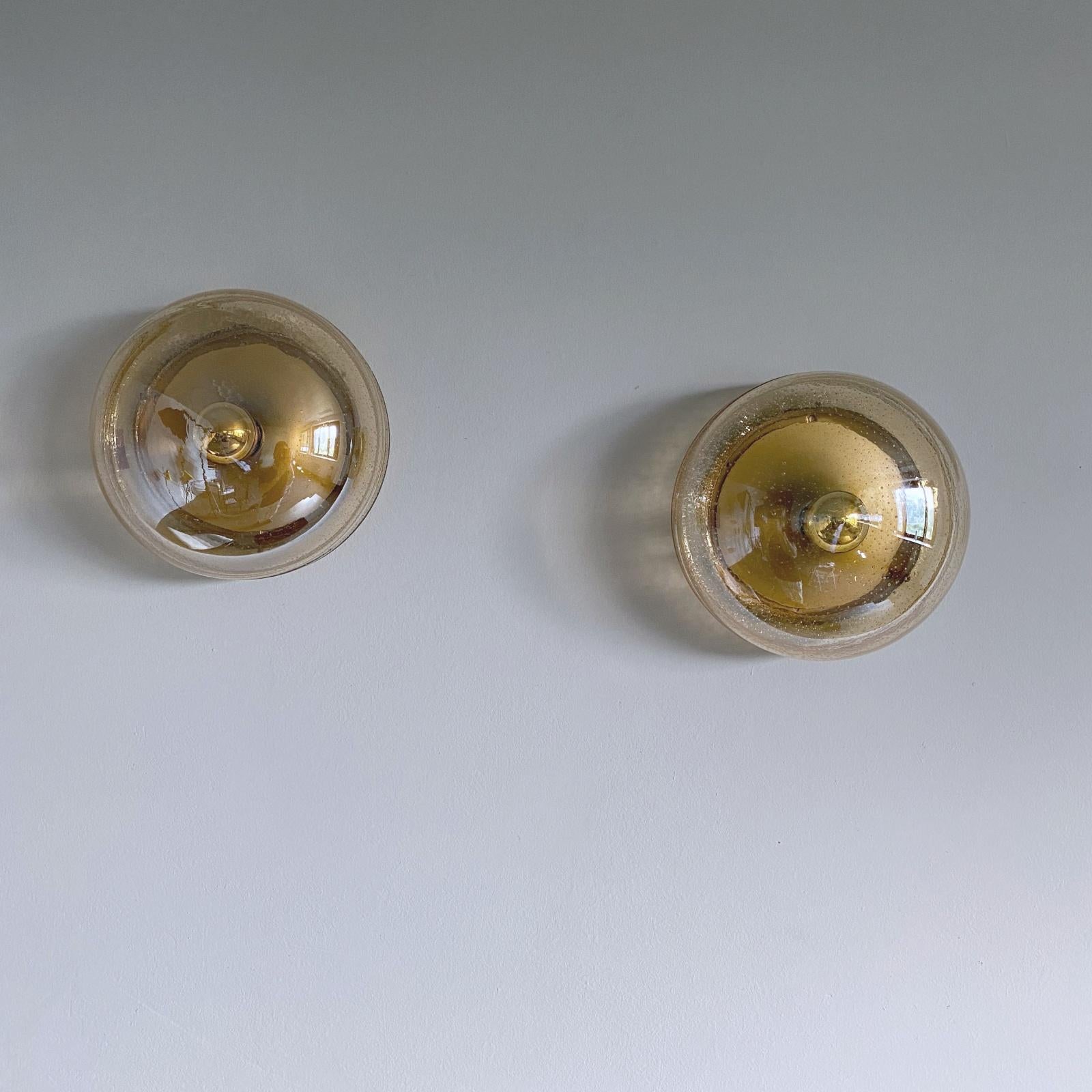 Pair of beautiful wall or ceiling lamps manufactured by Hillebrand in 1970s. They are featuring a brushed brass reflective base with a hand blown glass shade.
Fully working and tested condition with one E27 Edison socket each, the lamps work on